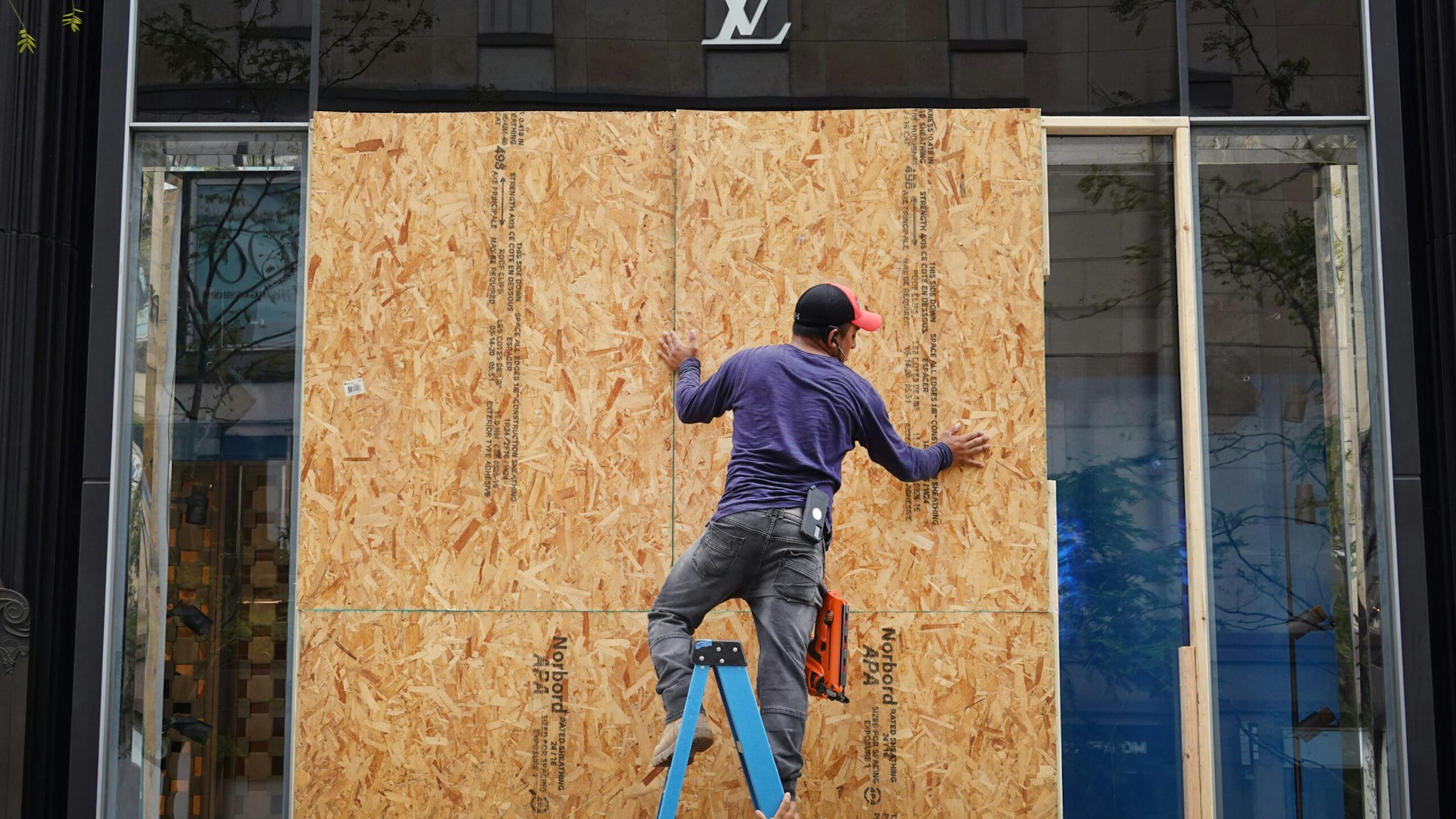 CHICAGO, ILLINOIS - AUGUST 10: Workers make repairs to the Louis Vuitton store after it was looted on August 10, 2020 in Chicago, Illinois. Police made more than 100 arrests during the night as widespread looting and disorderly conduct was reported downtown and other areas of the city. Officials believe the violence had apparently grown out of a shoot out between police and a suspect. (Photo by Scott Olson/Getty Images)