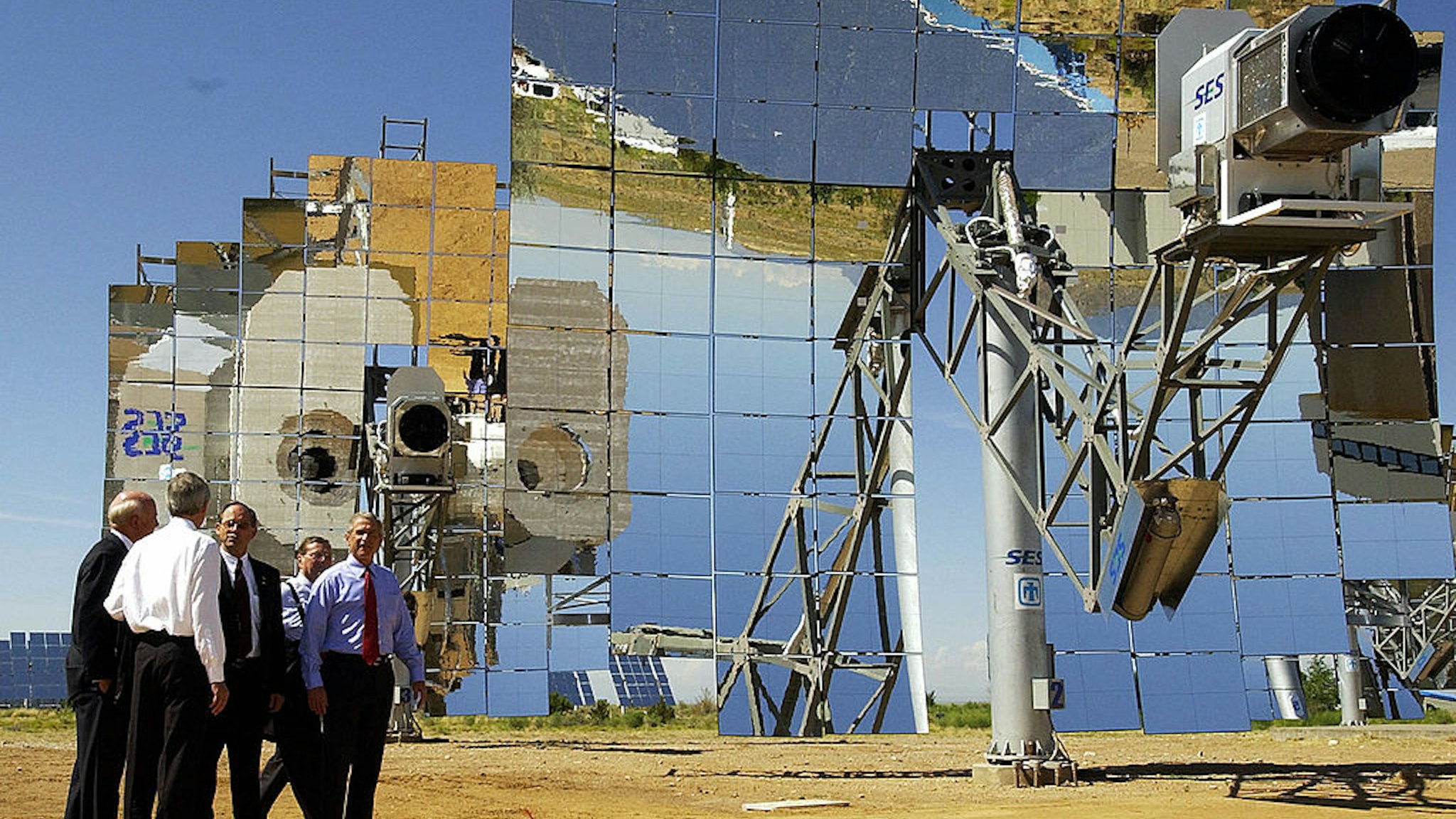 US President George W. Bush (R) walk past a parabolic dish during a tour of the Department of Energy's National Solar Thermal Test Facility at Sandia National Laboratories