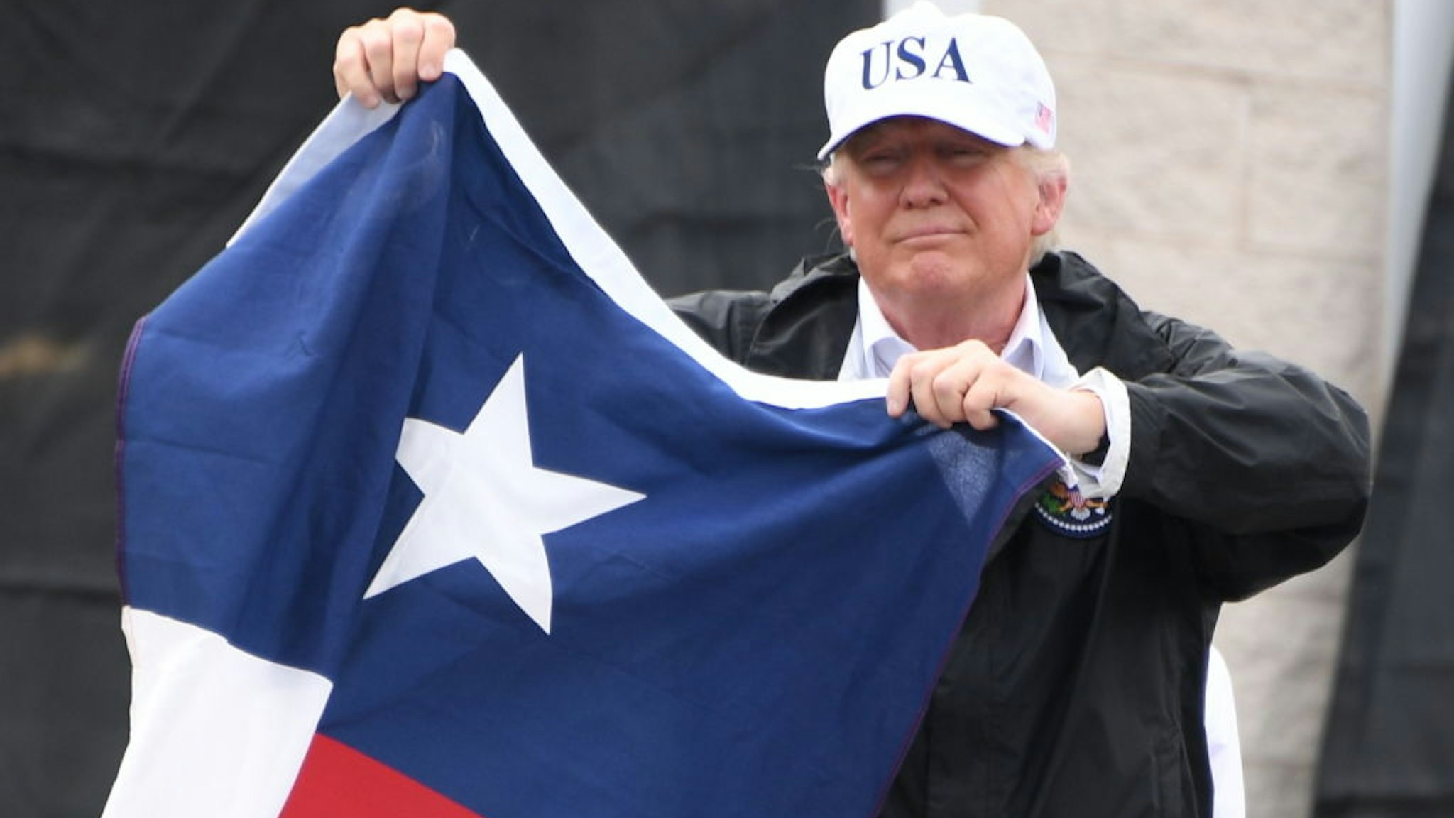 US President Donald Trump holds the state flag of Texas outside of the Annaville Fire House after attending a briefing on Hurricane Harvey in Corpus Christi, Texas on August 29, 2017.