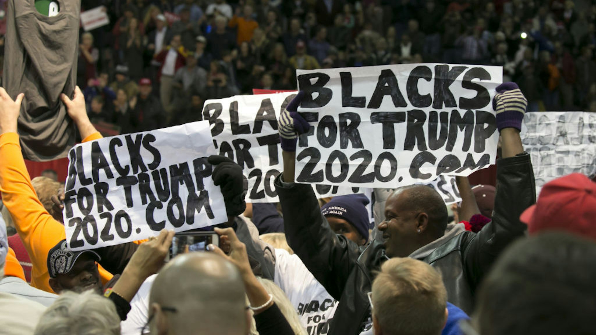 Attendees hold "Blacks For Trump" during a campaign rally with U.S. President Donald Trump in Pensacola, Florida, U.S., on Friday, Dec. 8, 2017.
