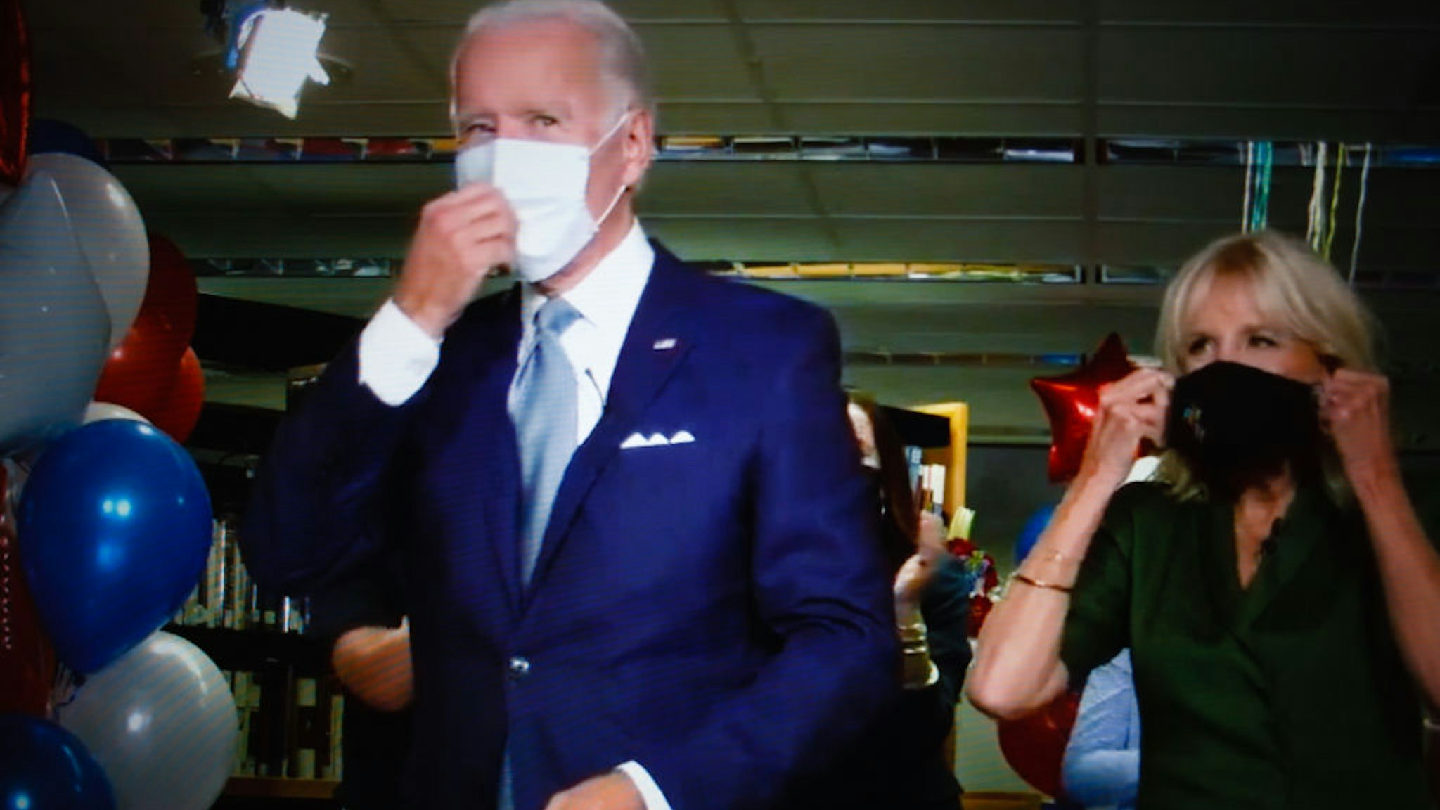 Former US Vice President Joe Biden, with wife Jill Biden, puts on a mask after formally becoming Democratic nominee for president during the virtual 2020 Democratic National Convention, livestreamed online and viewed on a laptop screen from London, England, on August 19, 2020. The four-day event, initially postponed from July, is taking place almost wholly remotely in response to the coronavirus pandemic. Biden will face President Donald Trump in the US presidential election on November 3. (Photo by David Cliff/NurPhoto via Getty Images)