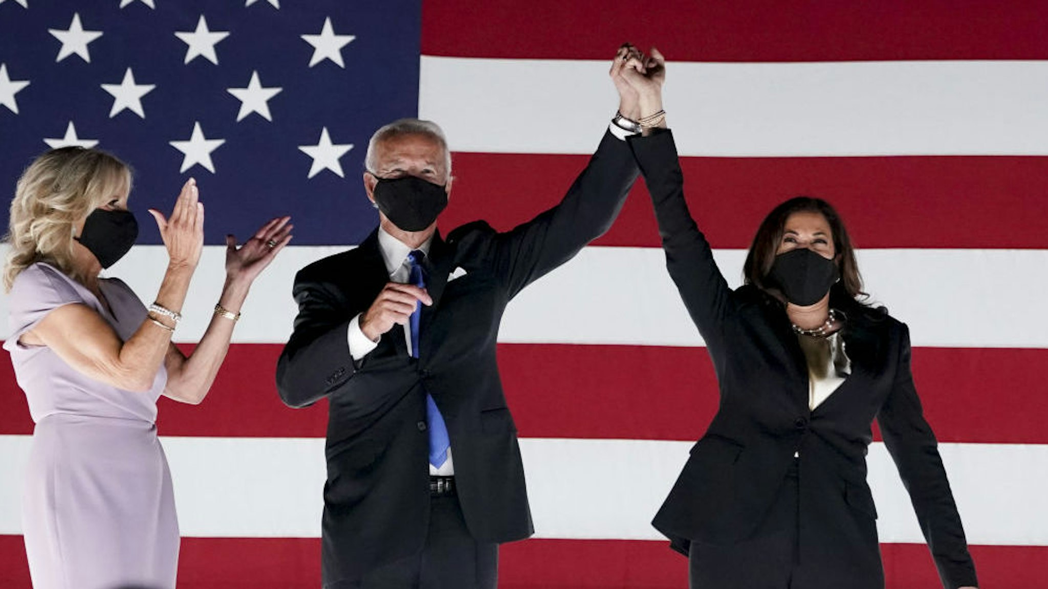 Former Vice President Joe Biden, Democratic presidential nominee, second left, and Senator Kamala Harris, Democratic vice presidential nominee, wear protective masks while holding hands next to Jill Biden, left, outside the Chase Center during the Democratic National Convention in Wilmington, Delaware, U.S., on Thursday, Aug. 20, 2020. Biden accepted the Democratic nomination to challenge President Donald Trump, urging Americans in a prime-time address to vote for new national leadership that will overcome deep U.S. political divisions. Photographer: Stefani Reynolds/Bloomberg
