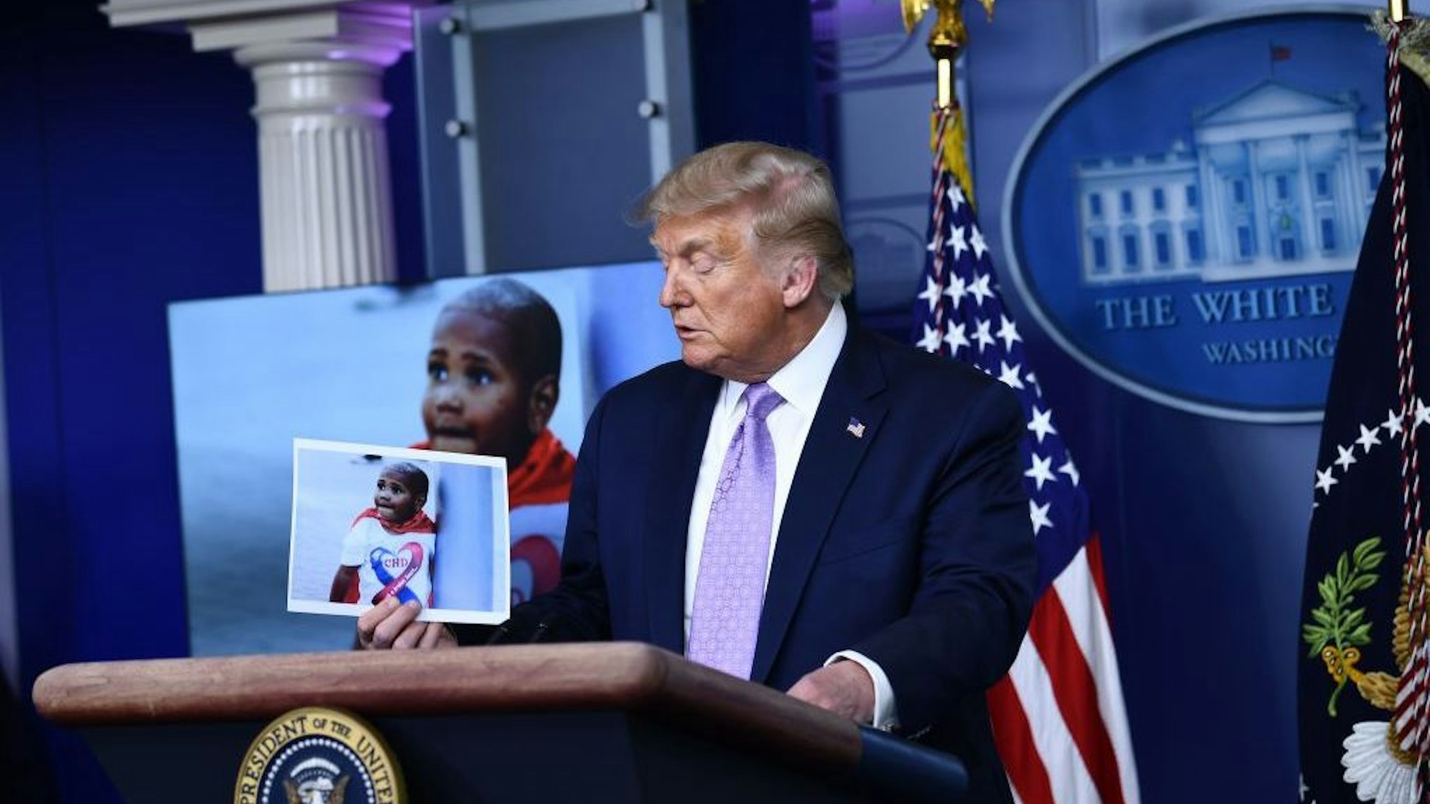 US President Donald Trump holds up a photo of LeGend Taliferro, a victim of a crime during a news conference in the Brady Briefing Room of the White House in Washington, DC, on August 13, 2020. (Photo by Brendan Smialowski / AFP) (Photo by BRENDAN SMIALOWSKI/AFP via Getty Images)