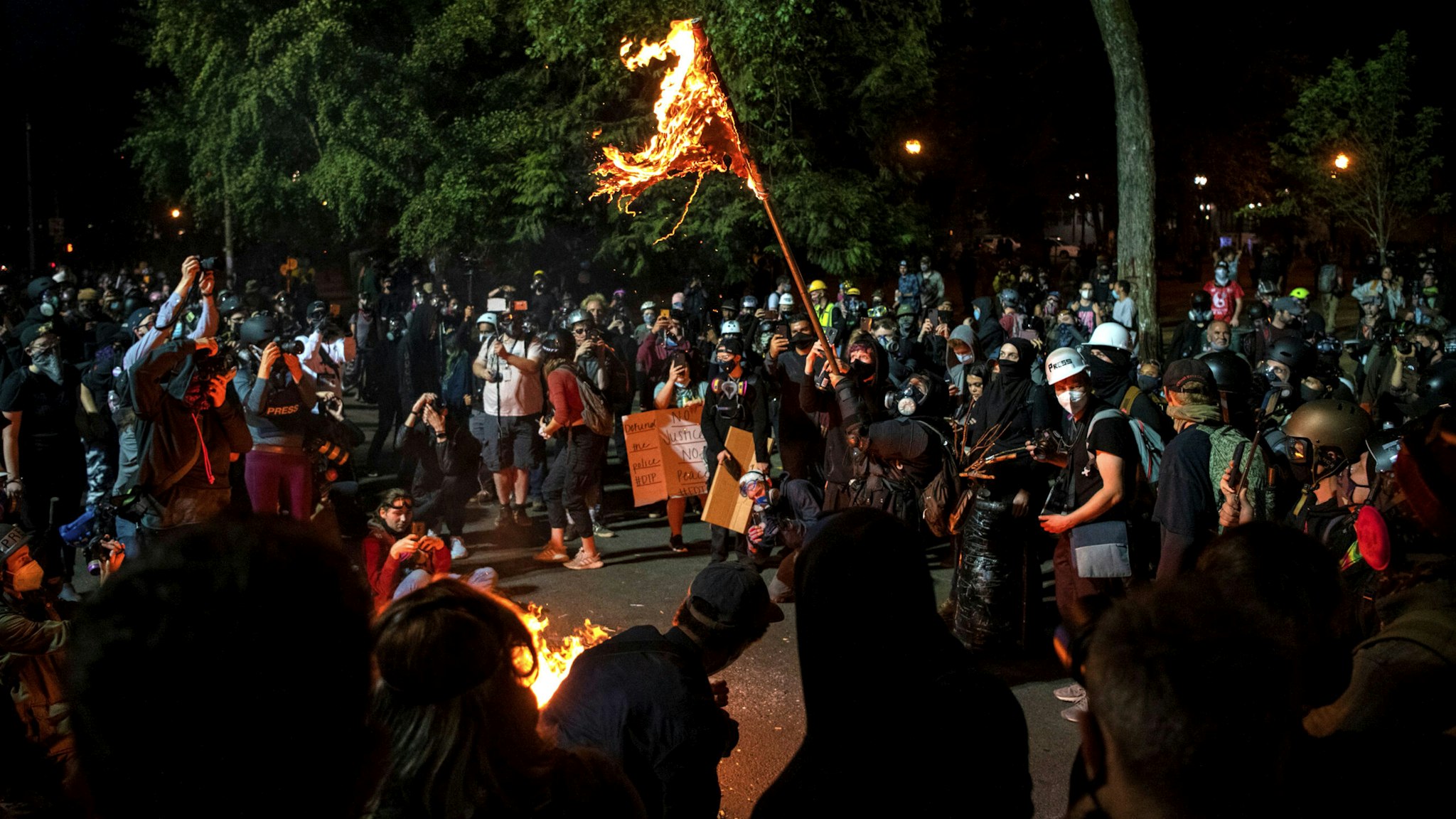 A demonstrator burns an American flag outside the Mark O. Hatfield United States Courthouse late Friday night during the protest on July 31, 2020 in Portland, Oregon. - US federal officers will stay in the protest-wracked city of Portland until local law enforcement officials finish a "cleanup of anarchists and agitators," the US President said.