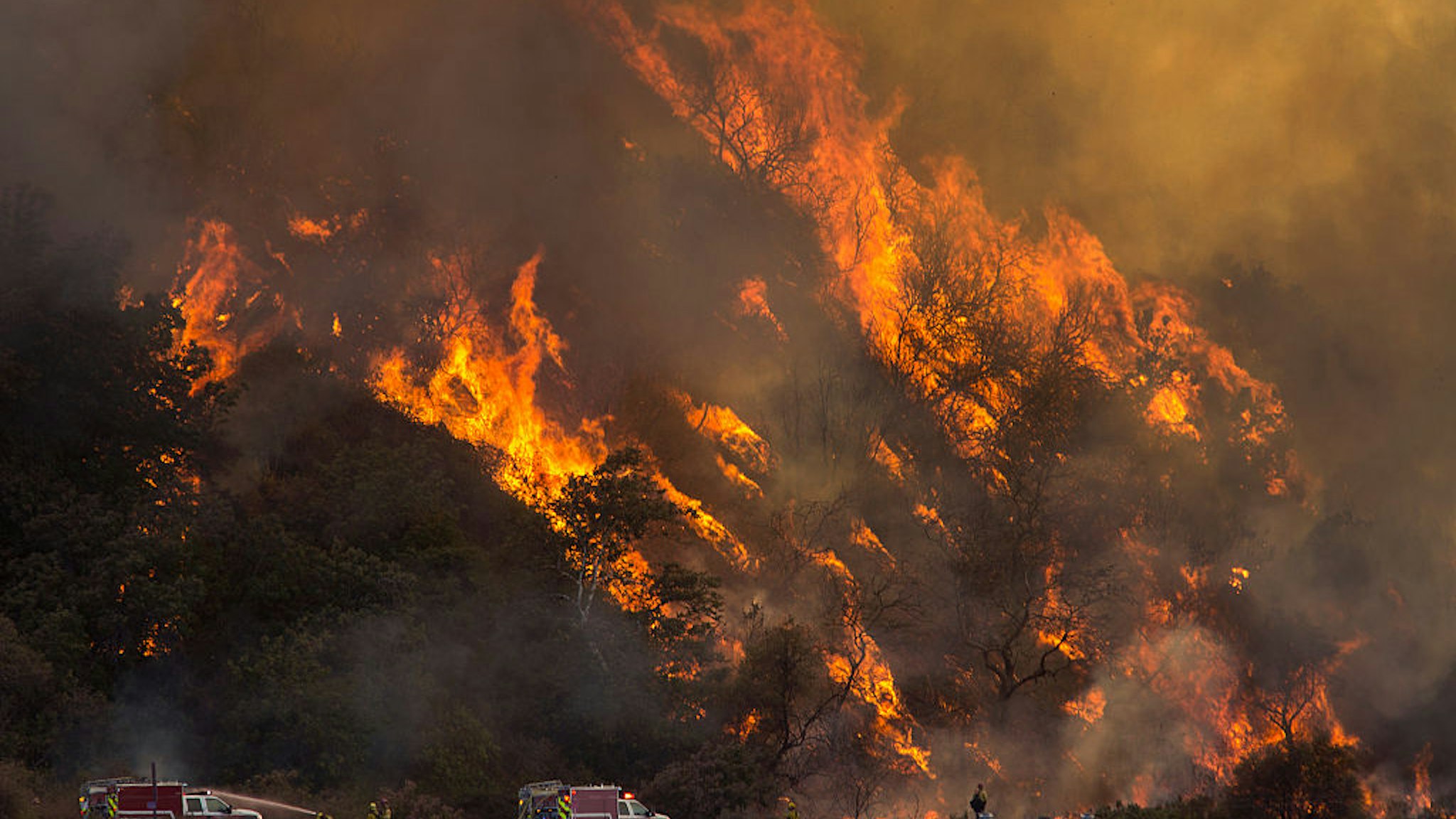 WRIGHTWOOD, CA - AUGUST 18: Flames spread up a hillside near firefighters at the Blue Cut Fire on August 18, 2016 near Wrightwood, California.. An unknown number of homes and businesses have burned and more than 80,000 people were ordered to evacuate as the wildfire spreads beyond 30,000 acres and threatens to expand into the ski resort town of Wrightwood. (Photo by David McNew/Getty Images)
