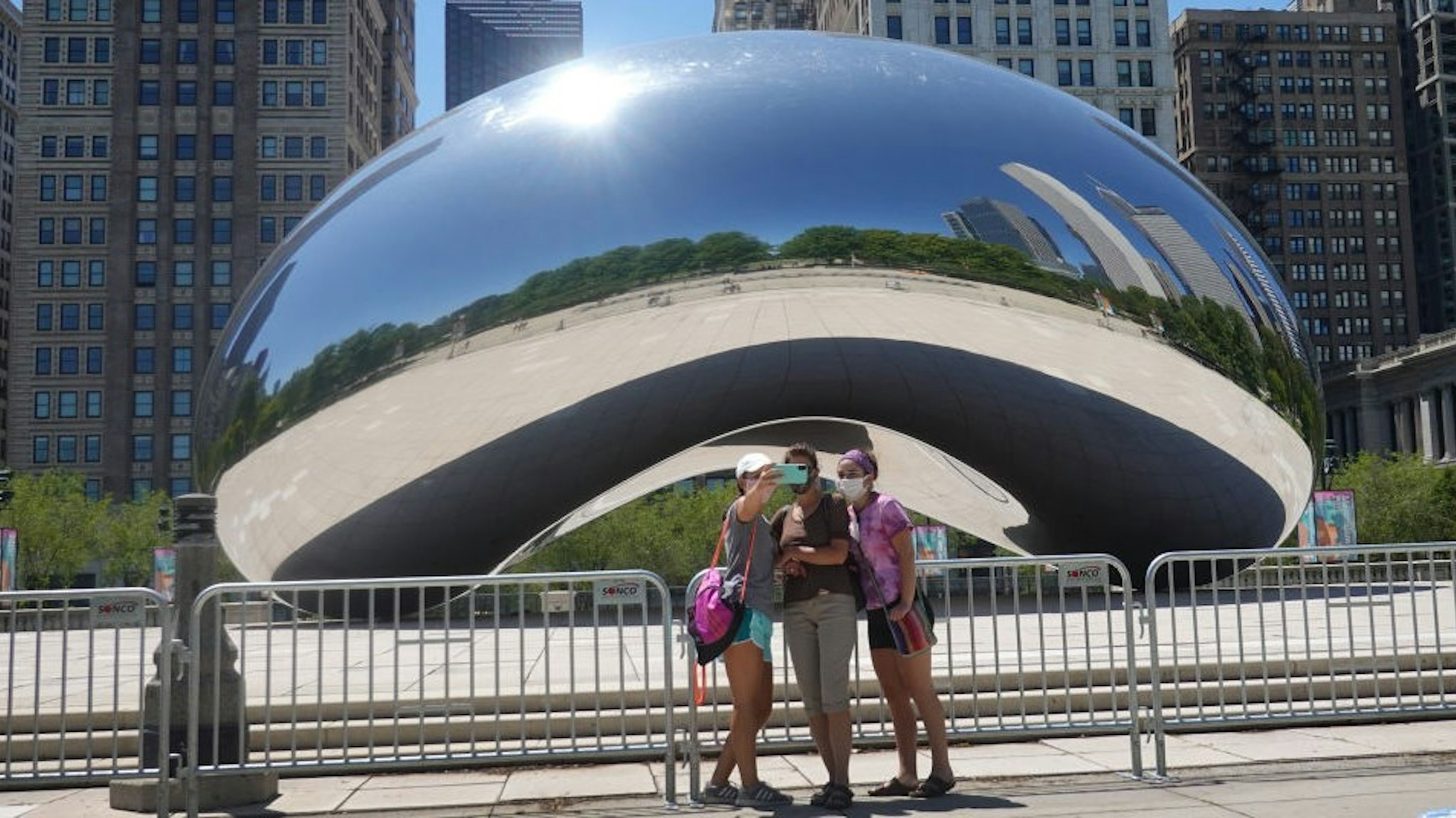 CHICAGO, ILLINOIS - JUNE 15: Visitors take pictures in front of the Cloud Gate sculpture in Millennium Park on June 15, 2020 in Chicago, Illinois. The park, which had been closed to visitors to help curtail the spread of the coronavirus COVID-19, partially reopened, with restrictions, to the public today. The park located in downtown Chicago is the most visited tourist attraction in the Midwest, attracting more than 12 million visitors annually. (Photo by