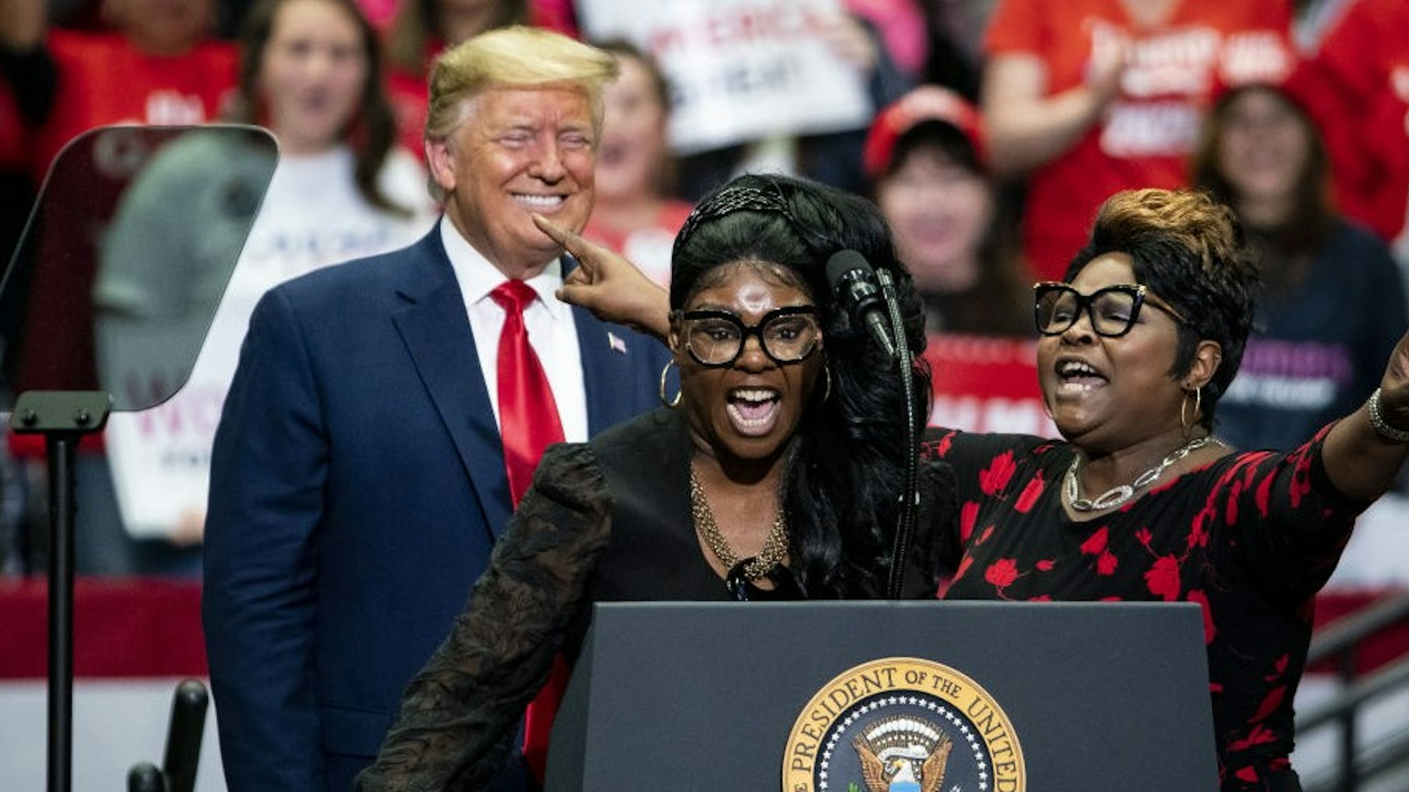 Social Media influencers and video bloggers Lynnette "Diamond" Hardaway, center, and Rochelle "Silk" Richardson, right, speak as U.S. President Donald Trump smiles during a rally in Charlotte, North Carolina, on Monday, March 2, 2020. Trump told reporters in the Oval Office on Monday that holding campaign rallies with thousands of attendees is "very safe" despite recent cases of the virus in the U.S. Photographer:
