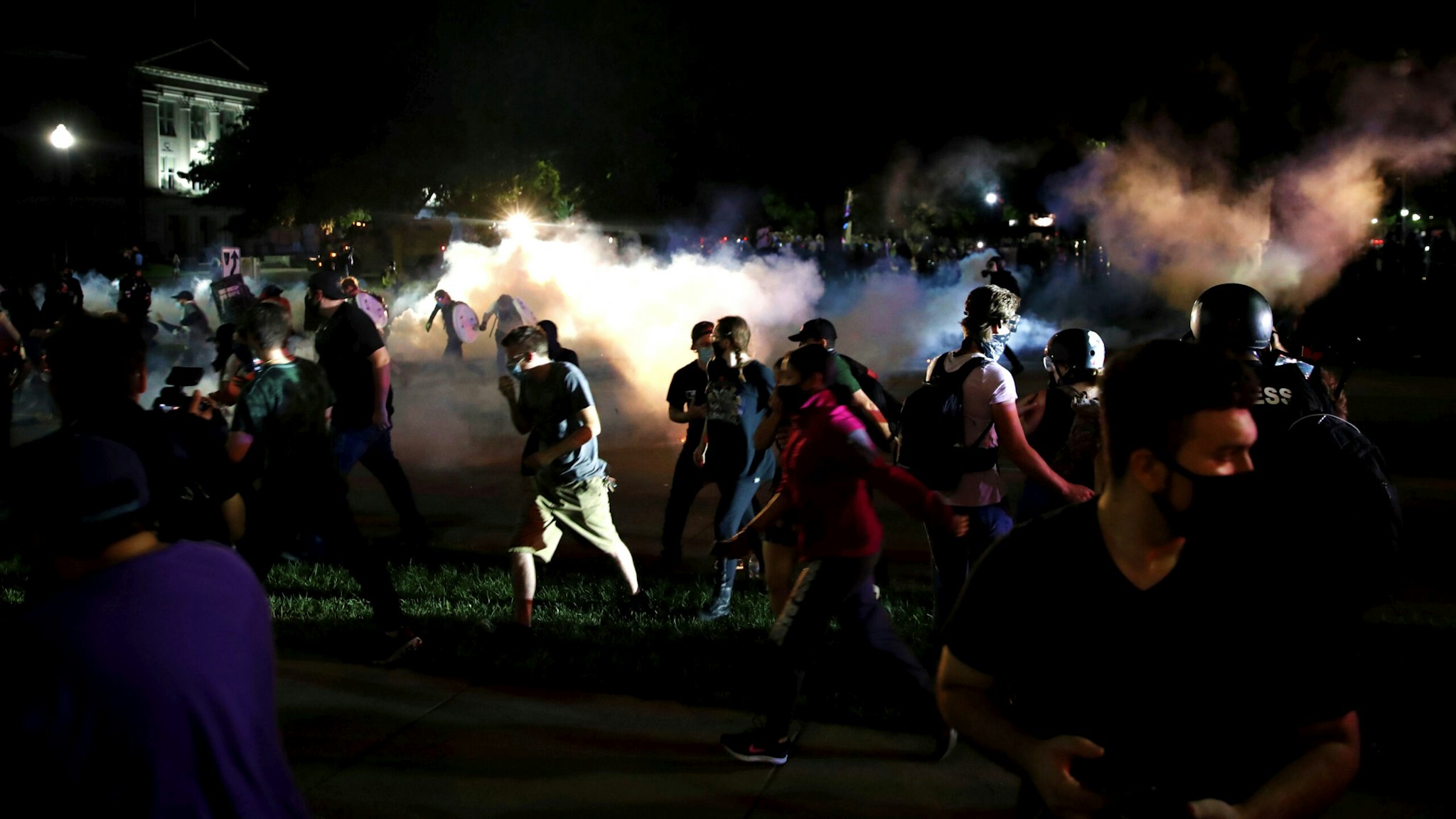 Protestors run for cover as police shoots teargas in an effort to disperse the crowd outside the County Courthouse during demonstrations against the shooting of Jacob Blake in Kenosha, Wisconsin on August 25, 2020. - The mother of a black man shot repeatedly in the back by Wisconsin police called August 25 for calm after two nights of violent protests, as her lawyer said it would take a "miracle" for her son to walk again.
