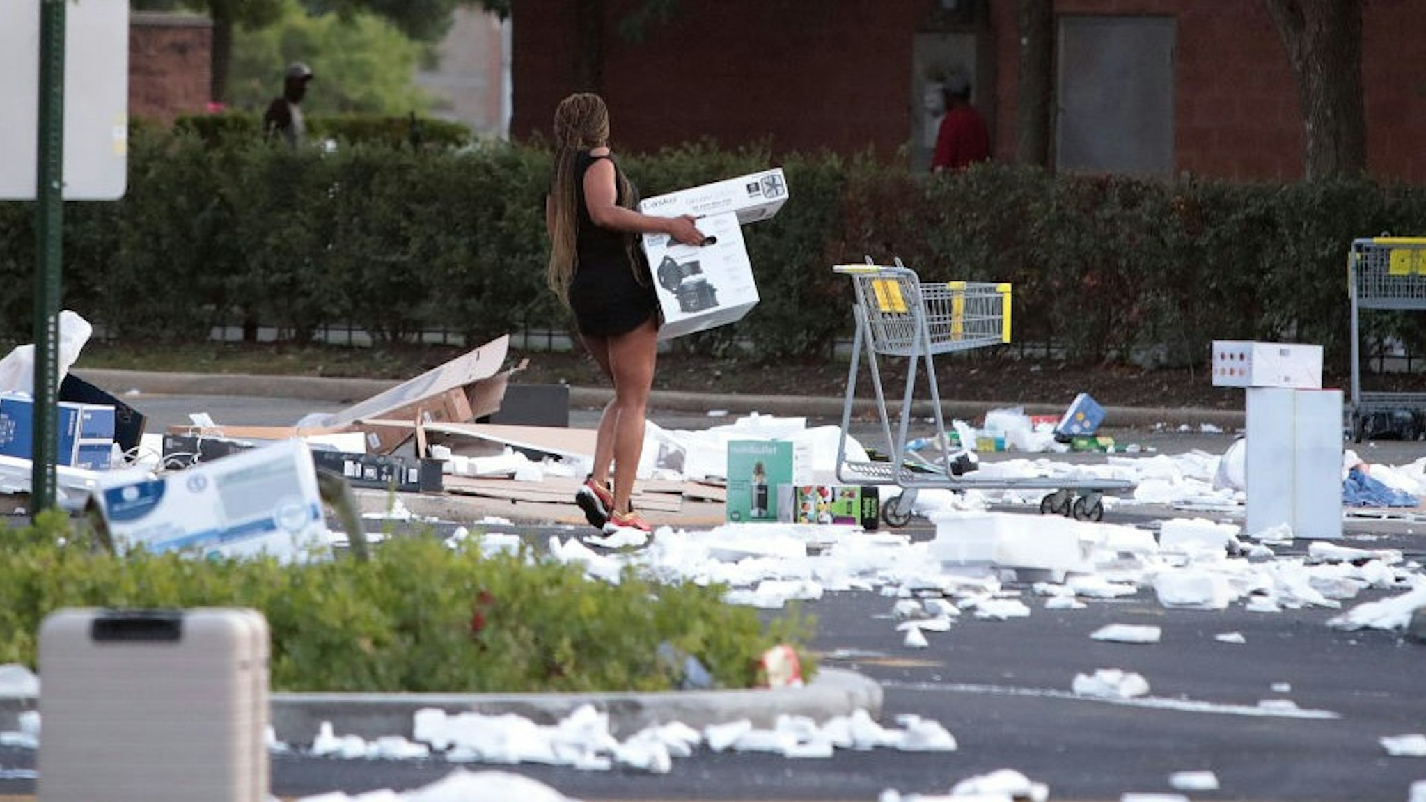 CHICAGO, ILLINOIS - AUGUST 10: A person carries a box near a looted Best Buy store seen after parts of the city had widespread looting and vandalism, on August 10, 2020 in Chicago, Illinois. Police made several arrests during the night of unrest and recovered at least one firearm. (Photo by
