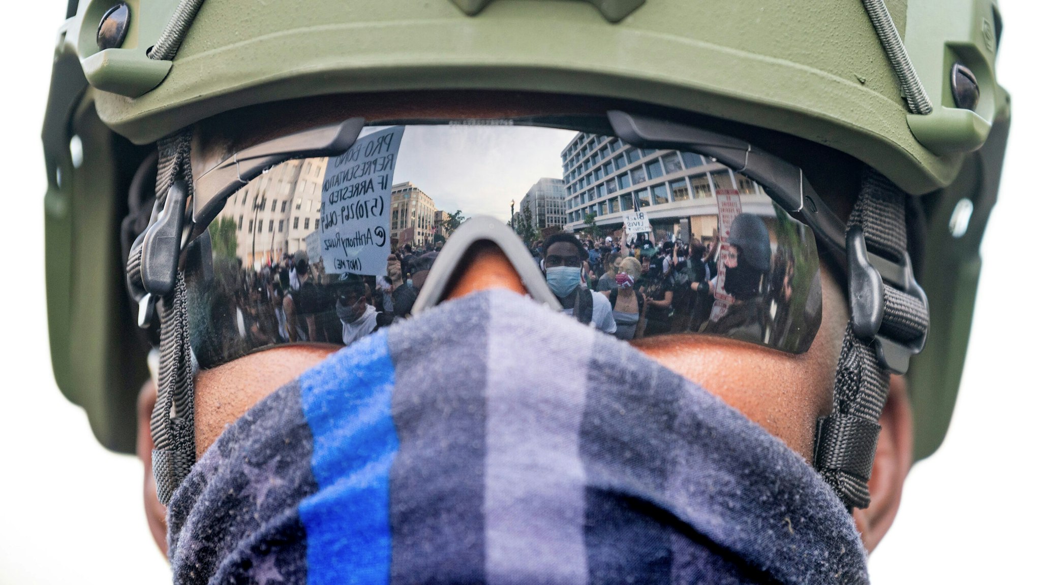 Protesters are reflected in the glasses of an US Army National Guard member as they demonstrate the death of George Floyd near the White House on June 3, 2020, in Washington, DC. - Former Minneapolis police officer Derek Chauvin, who kneeled on the neck of George Floyd who later died, will now be charged with second-degree murder, and his three colleagues will face charges of aiding and abetting second-degree murder, court documents revealed on June 3.
