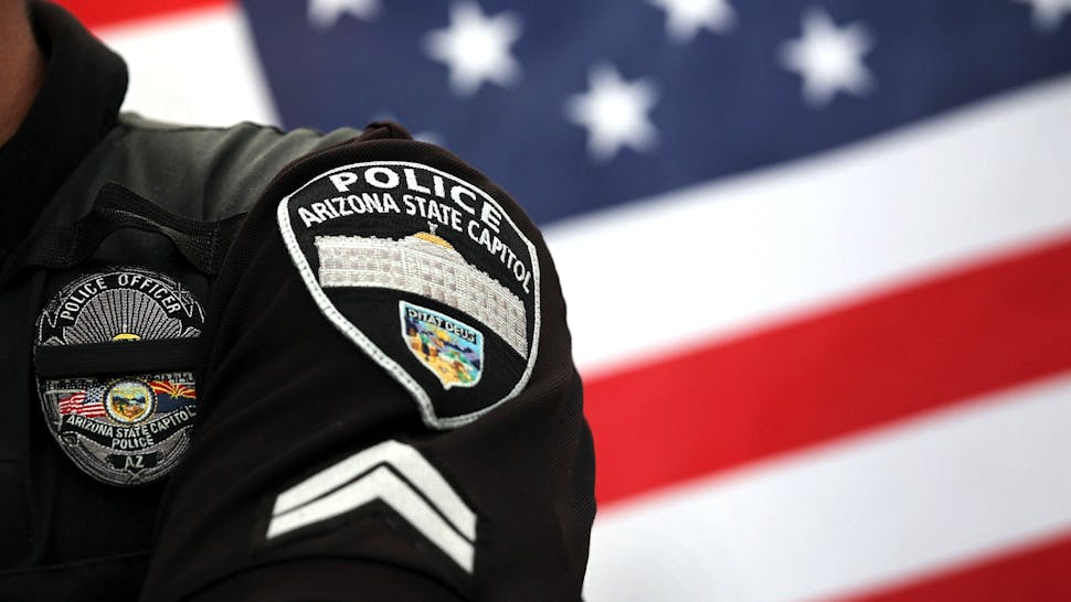 PHOENIX - JULY 31: A policeman stands guard as supporters and opponents of Arizona's immigration enforcement law face off during a demonstration against illegal immigration on July 31, 2010 in Phoenix, Arizona. Hundreds of supporters of Arizona's immigration enforcement law SB 1070 and Tea Party supporters rallied in favor of the law at the state capitol building. Several dozen opponents of the law turned out to stage a counter protest.