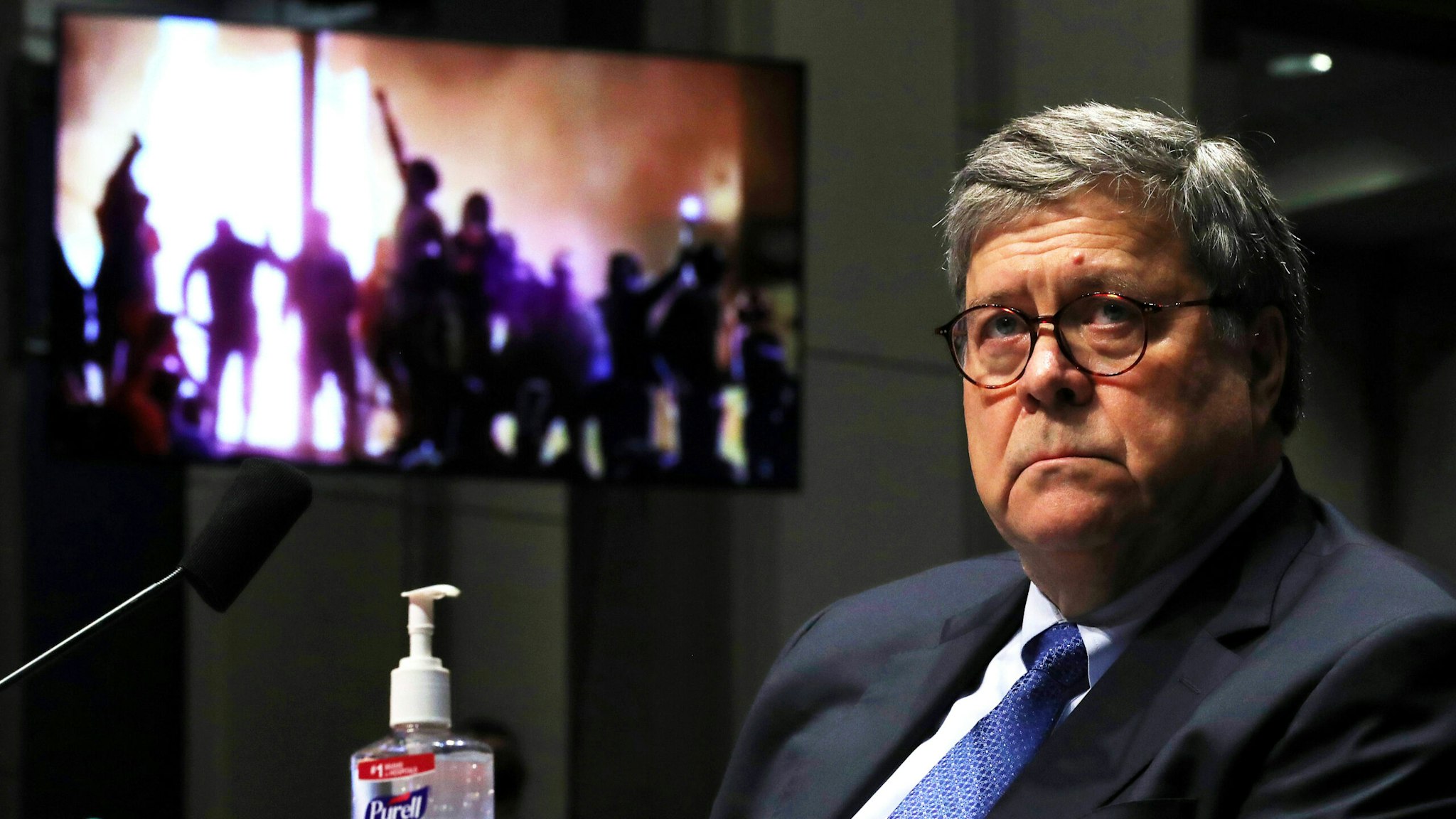 Attorney General William Barr watches a Republican Exhibit video of people rioting, during the House Judiciary Committee hearing in the Congressional Auditorium at the US Capitol Visitors Center July 28, 2020 in Washington, DC. - In his first congressional testimony in more than a year, Barr is expected to face questions from the committee about his deployment of federal law enforcement agents to Portland, Oregon, and other cities in response to Black Lives Matter protests; his role in using federal agents to violently clear protesters from Lafayette Square near the White House last month before a photo opportunity for President Donald Trump in front of a church; his intervention in court cases involving Trump's allies Roger Stone and Michael Flynn; and other issues.