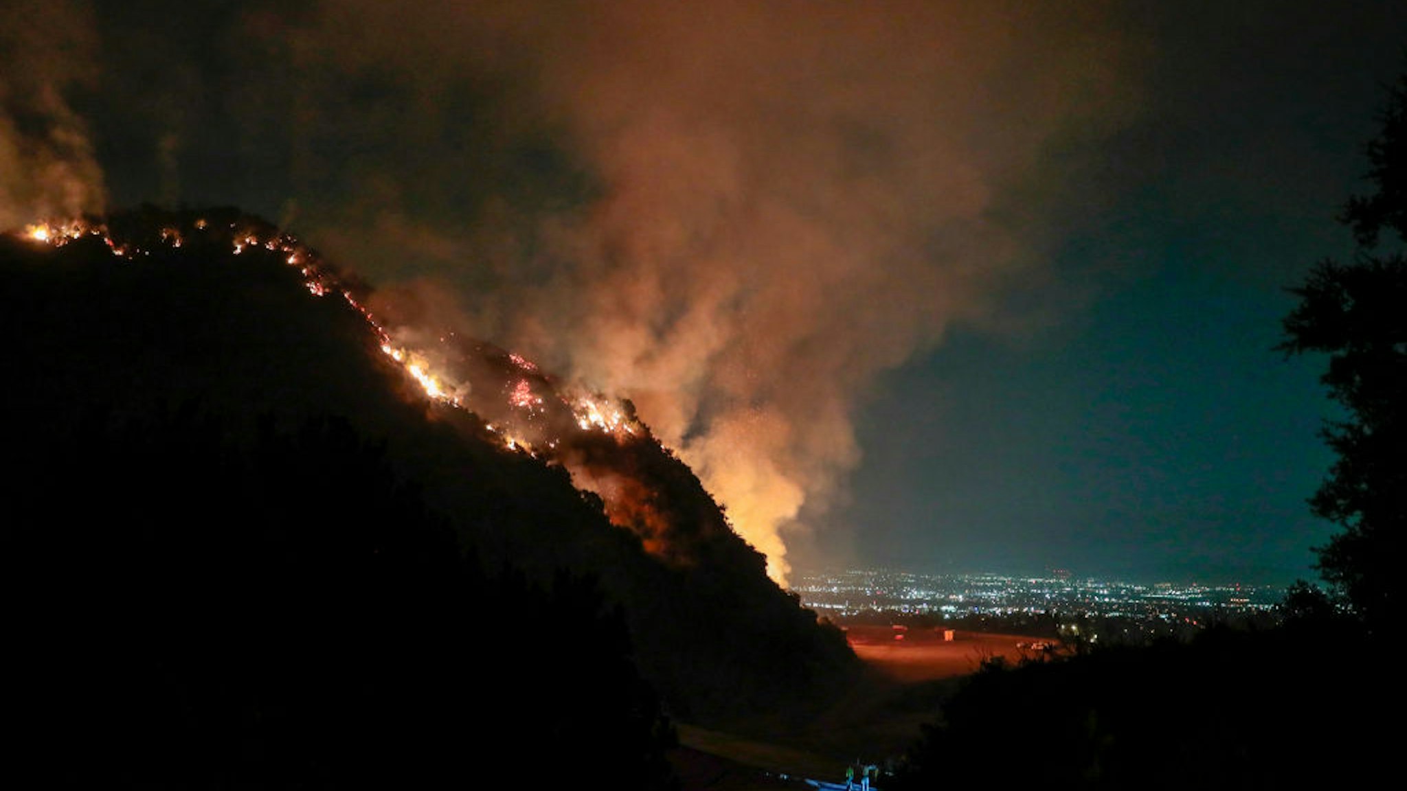 Firefighters look on from Sawpit Canyon as a control burn fires on a hillside overlooking the San Gabriel Valley as the Bobcat Fire continues to burn into its second week. (Robert Gauthier/ Los Angeles Times via Getty Images)