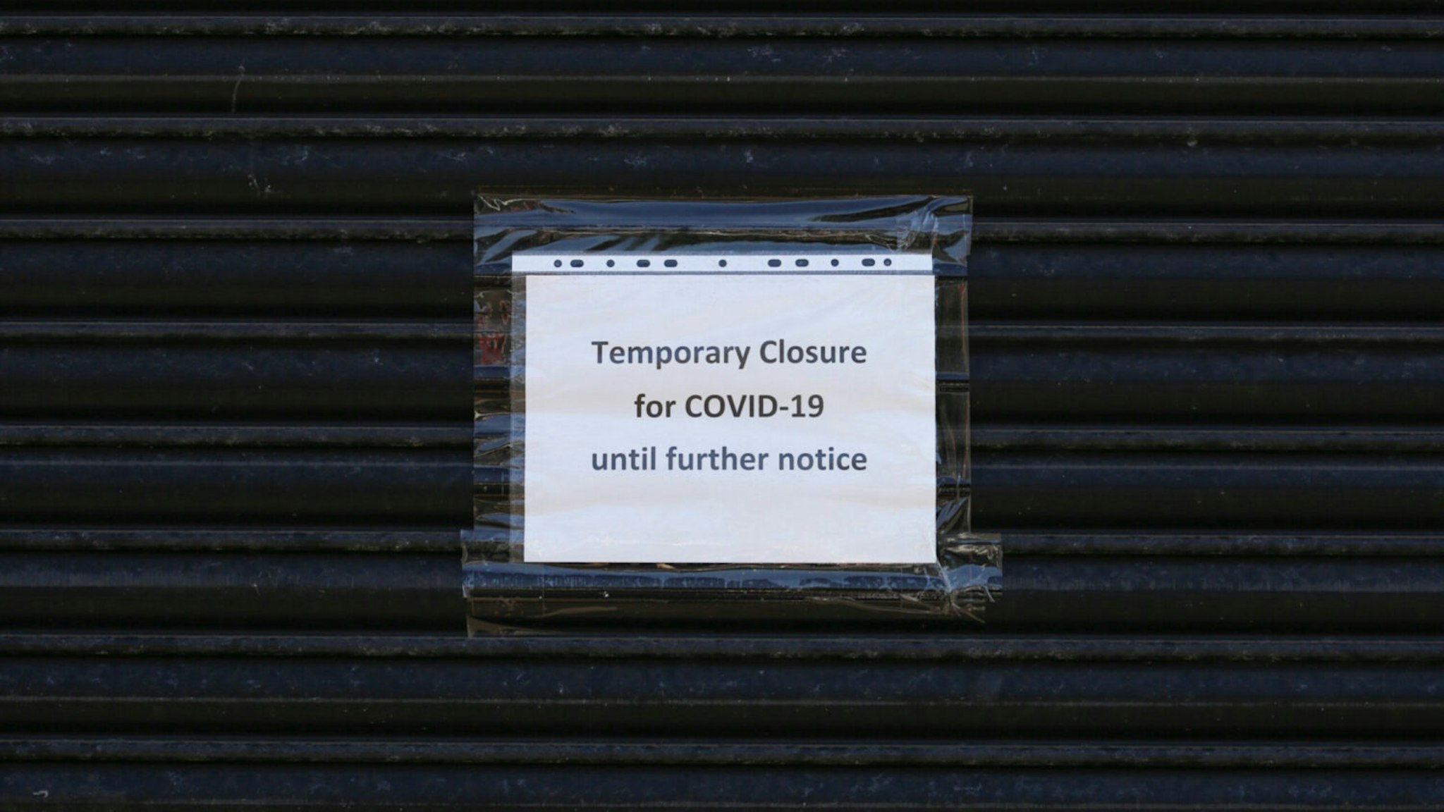 Sign on anonymous shuttered building saying ‘Temporary closure for Covid 19’ during the Covid 19 coronavirus pandemic.