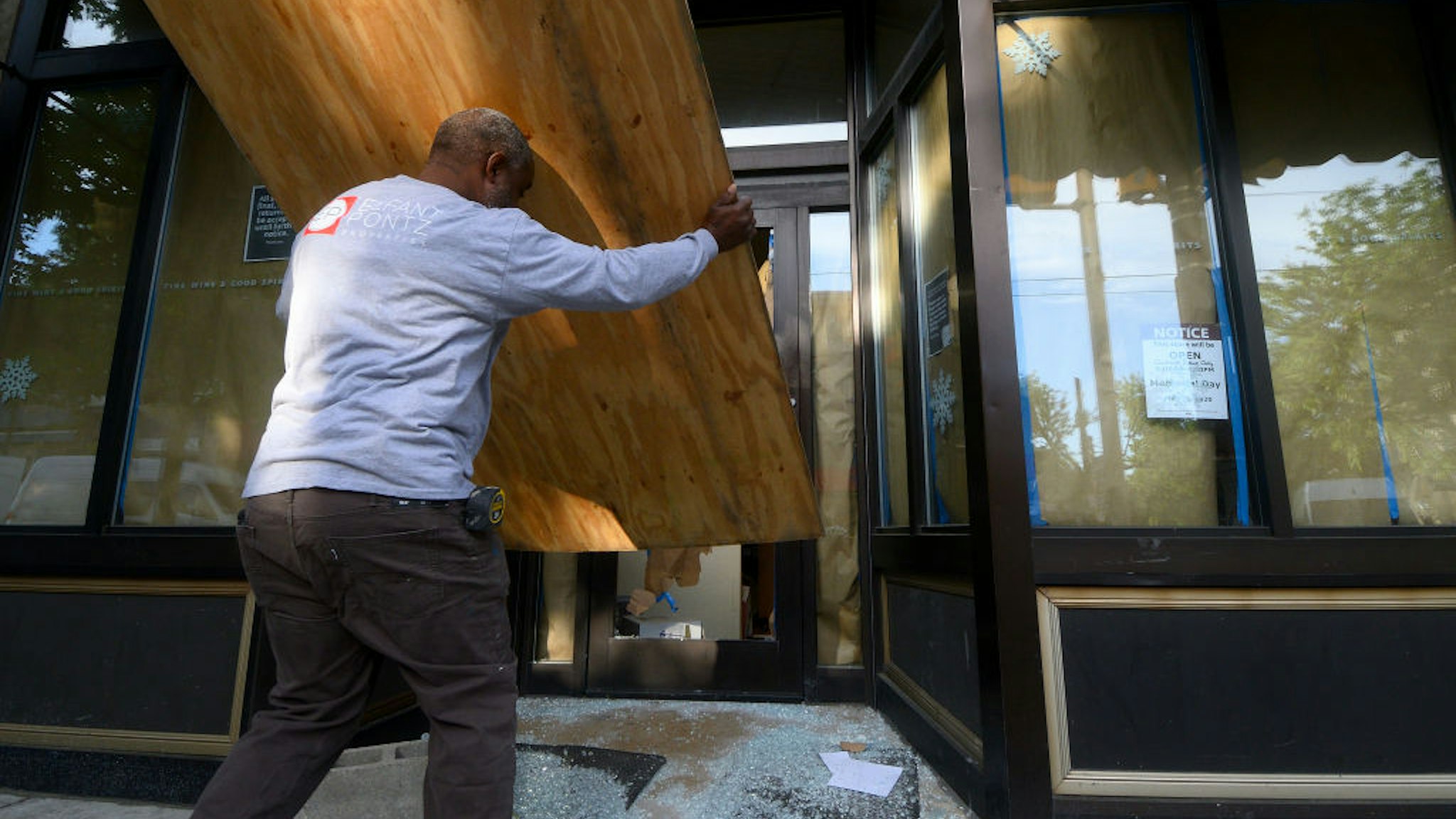 A passerby voluntarily boards up the state-owned wine and liquor store after it is vandalized overnight, in the Mt Airy neighborhood in Philadelphia, PA on June 1, 2020. On Monday morning National Guard troops arrived to assist policing the city after two days of unrest and protests over the death of George Floyd. (Photo by Bastiaan Slabbers/NurPhoto via Getty Images)