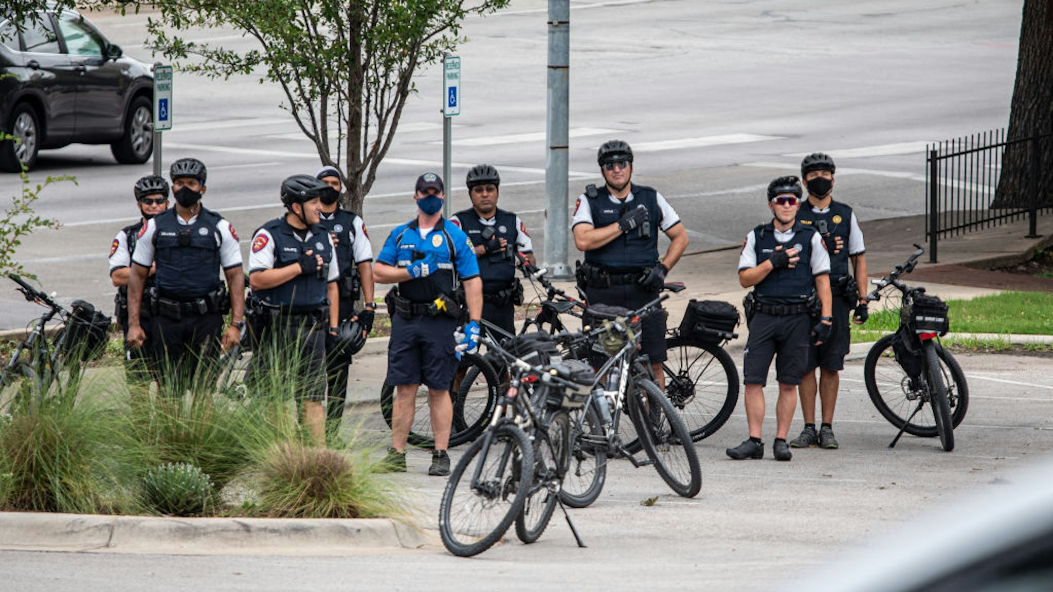 Police officers hold their hands over their hearts as a demonstrator sings the National Anthem during a "Bar Lives Matter" protest in Austin, Texas, U.S., on Tuesday, June 30, 2020.
