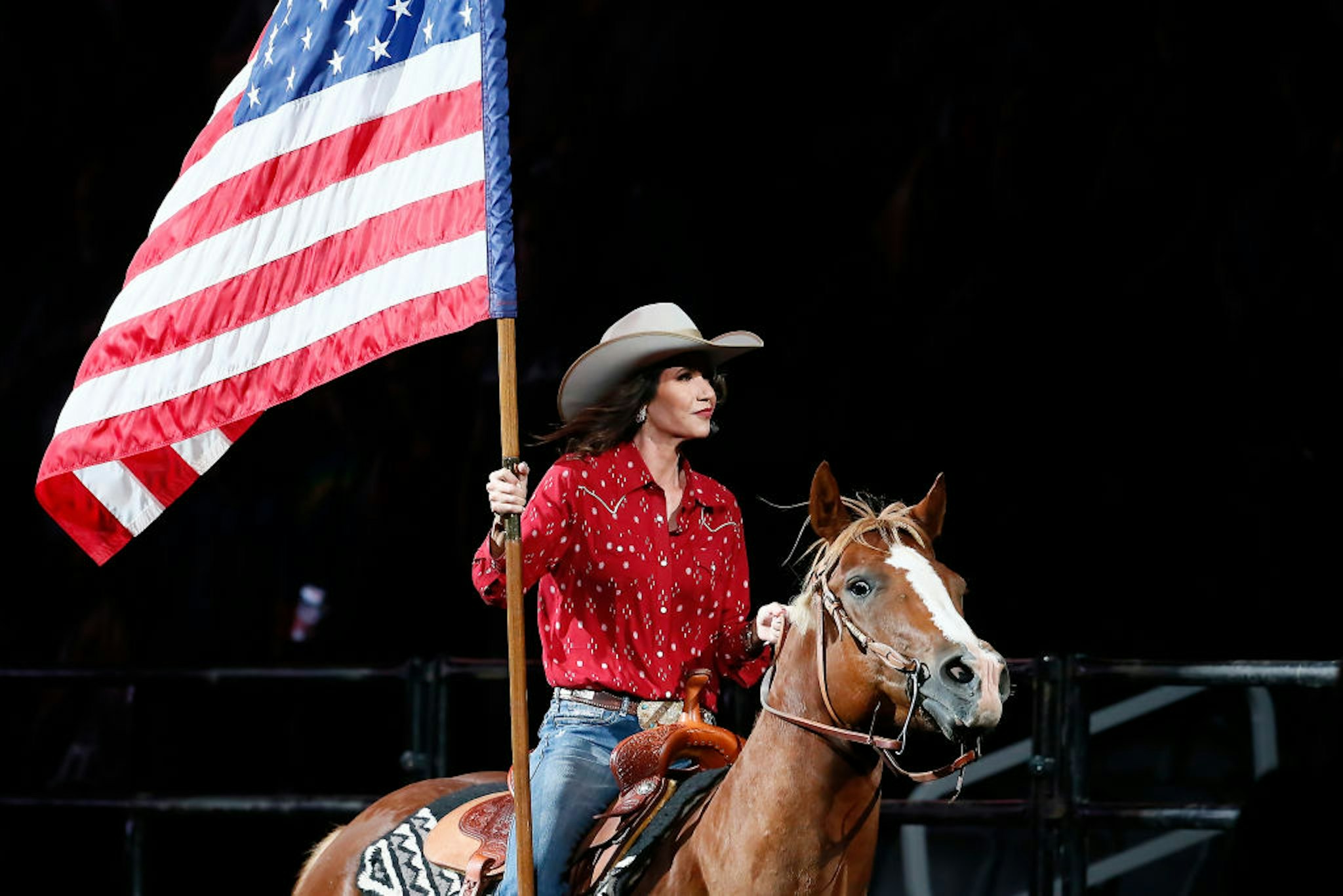 South Dakota's Governor Kristi Noem holds the U.S flag riding a horse during the Monster Energy Team Challenge, on July 11, 2020, at the Denny Sanford PREMIER Center, Sioux Falls, SD.