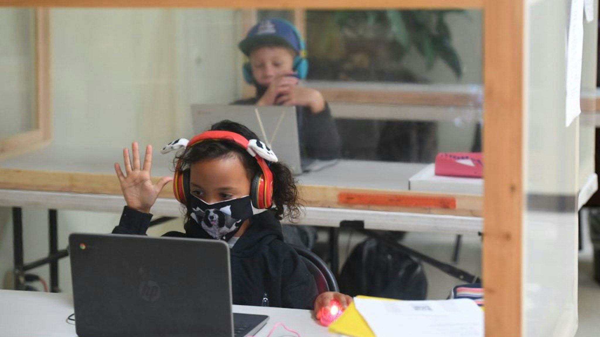 Students follow along remotely with their regular school teacher's online live lesson from separated by plastic barriers at STAR Eco Station Tutoring & Enrichment Center on September 10, 2020 in Culver City, California.