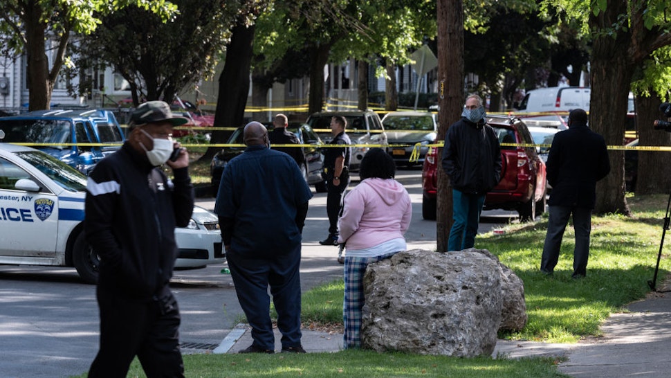 People look on as police investigate a crime scene after a shooting at a backyard party on September 19, 2020, Rochester, New York.