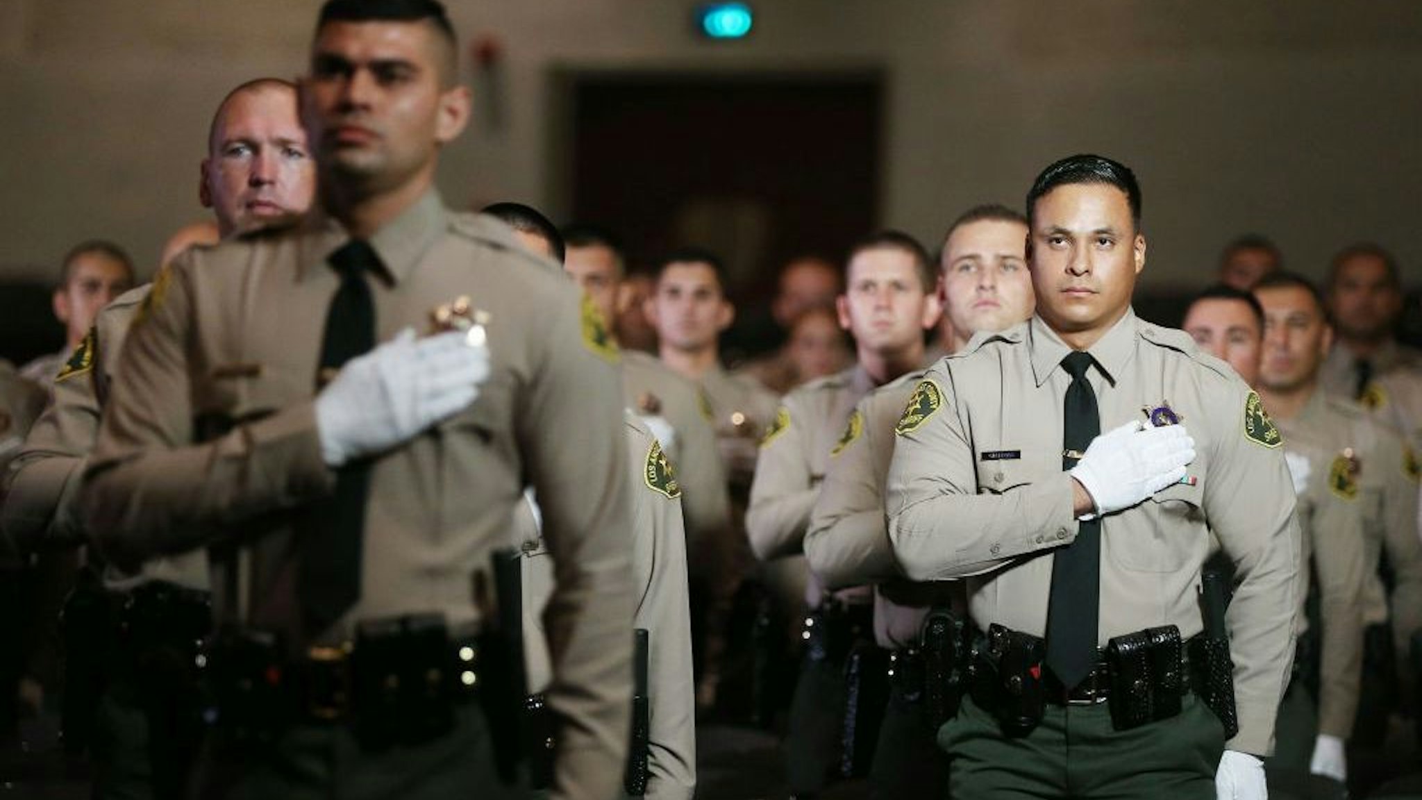 MONTEREY PARK, CALIFORNIA - AUGUST 21: Graduates of Los Angeles County Sheriff's Department Academy Class 451 stand for the pledge of allegiance at their graduation ceremony at East Los Angeles College amid the COVID-19 pandemic on August 21, 2020 in Monterey Park, California. Graduates were seated with social distancing and family members were not allowed inside the ceremony due to restrictions in place to prevent the spread of the coronavirus. (Photo by Mario Tama/Getty Images)