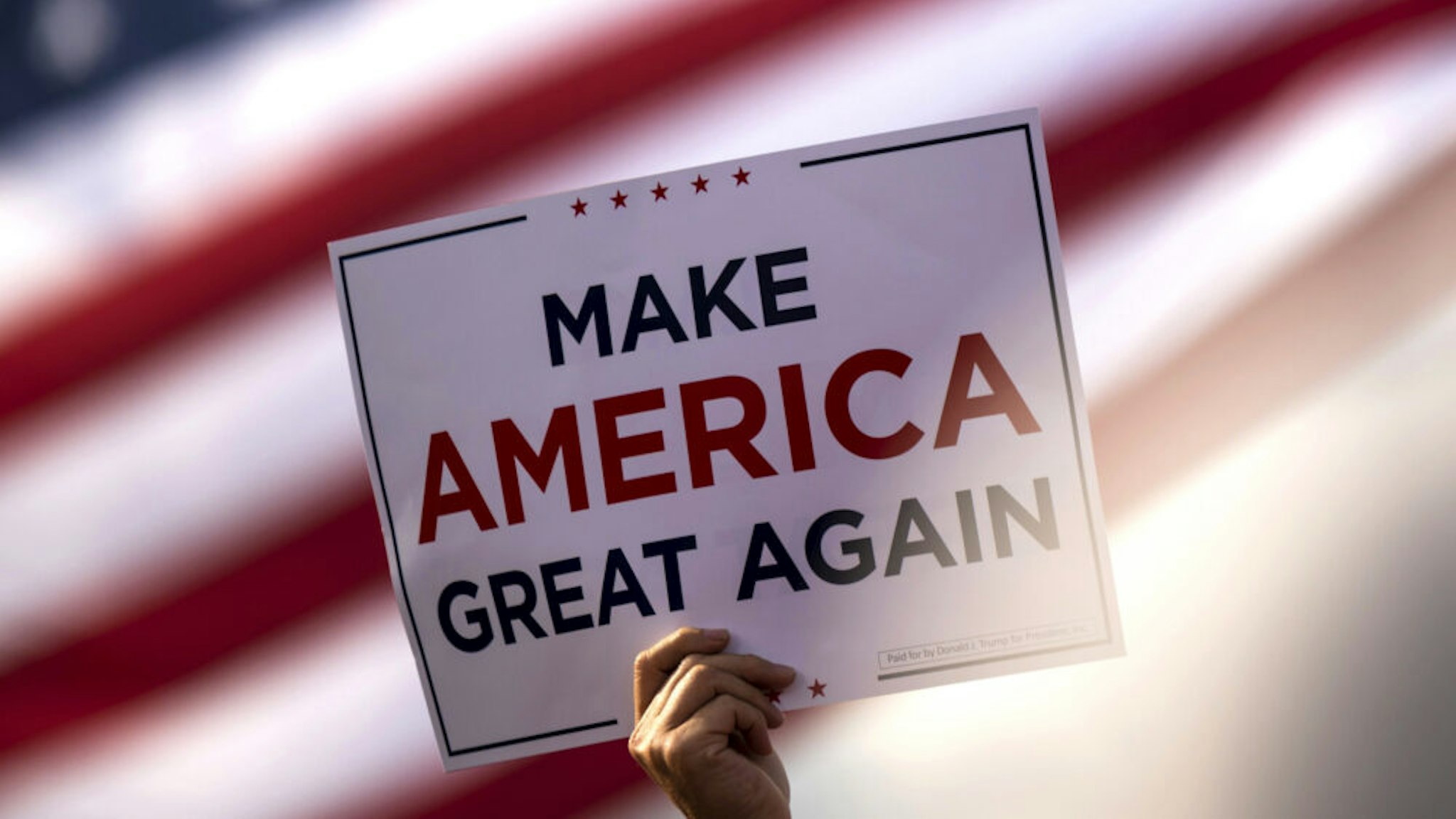 BEMIDJI, MN - SEPTEMBER 18: A man waves a "Make America Great Again" sign before President Donald Trump arrives for a rally at the Bemidji Regional Airport on September 18, 2020 in Bemidji, Minnesota. Trump and challenger, Democratic presidential nominee and former Vice President Joe Biden, are both campaigning in Minnesota today.
