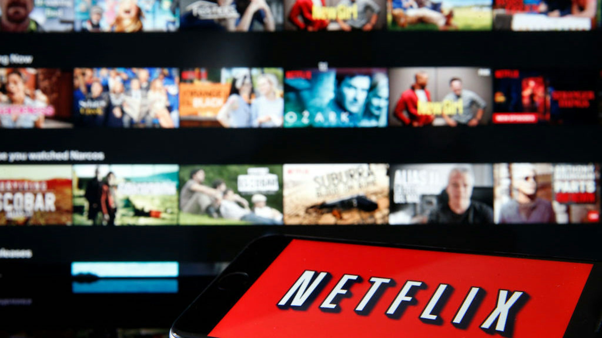 In this photo illustration, the Netflix media service provider's logo is displayed on the screen of an iPhone in front of a television screen on March 28, 2020 in Paris, France. Faced with the coronavirus crisis, Netflix will reduce visual quality for the next 30 days, in order to limit its use of bandwidth. (Photo Illustration by Chesnot/Getty Images)