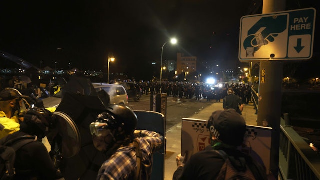 ROCHESTER, NEW YORK - SEPTEMBER 04: Demonstrators shield themselves from pepper balls as police officers attempt to clear the streets after a march for Daniel Prude on September 04, 2020 in Rochester, New York. Prude died after being arrested on March 23, by Rochester police officers who had placed a "spit hood" over his head and pinned him to the ground while restraining him. Mayor Lovely Warren announced yesterday the suspension of seven officers involved in the arrest.