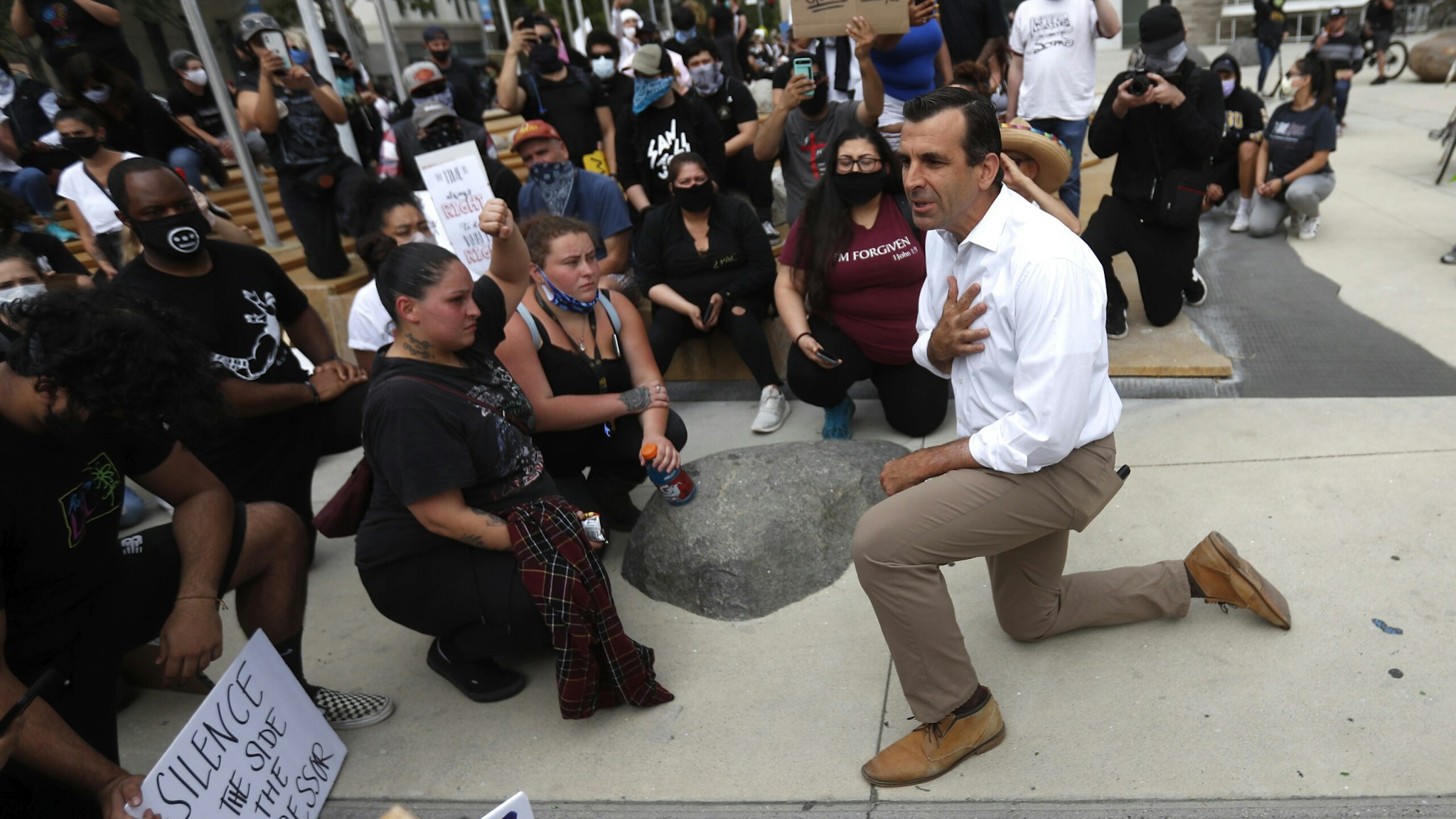 SAN JOSE, CALIFORNIA - MAY 31: Protesters listen to San Jose Mayor Sam Liccardo as he takes a knee during a protest of the killing of George Floyd outside of San Jose City Hall in downtown San Jose, Calif., on Sunday, May 31, 2020.