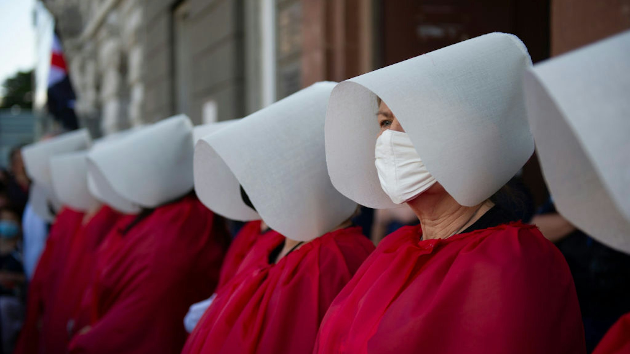 Demonstrators wearing protective face masks are dressed as the Handmaids from the dystopian novel The Handmaid's Tale from the Canadian author Margaret Atwood perform during an anti-domestic violence protest on July 24, 2020 in Warsaw, Poland. Thousands of demonstrators took part in a protest against government plan to pull out of an international treaty on preventing and combating domestic violence. (Photo by Aleksander Kalka/NurPhoto via Getty Images)