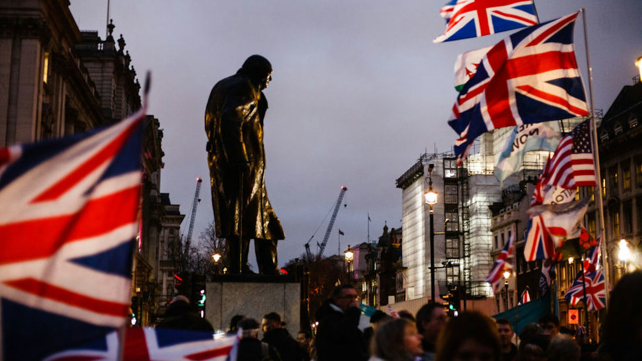 The statue of Britain's wartime leader Winston Churchill stands surrounded by Union Jack flags in London, England, on January 31, 2020. Britain's exit from the European Union, today at 11pm UK time (midnight in Brussels), comes more than three and a half years since the country's deeply polarising EU membership referendum, yet the moment brings to an end only the first stage of the Brexit saga, with the UK's future relationship with the bloc still to be negotiated. British Prime Minister Boris Johnson has insisted that the 11-month transition period, wherein arrangements continue practically unchanged, will not be extended past its December 31 expiration date and that a trade deal can be reached in that time. Critics argue that any such deal will have to be severely constrained in ambition to be negotiated in such a short period, and that workers' rights and other protections may be lost in the process. (Photo by David Cliff/NurPhoto via Getty Images)
