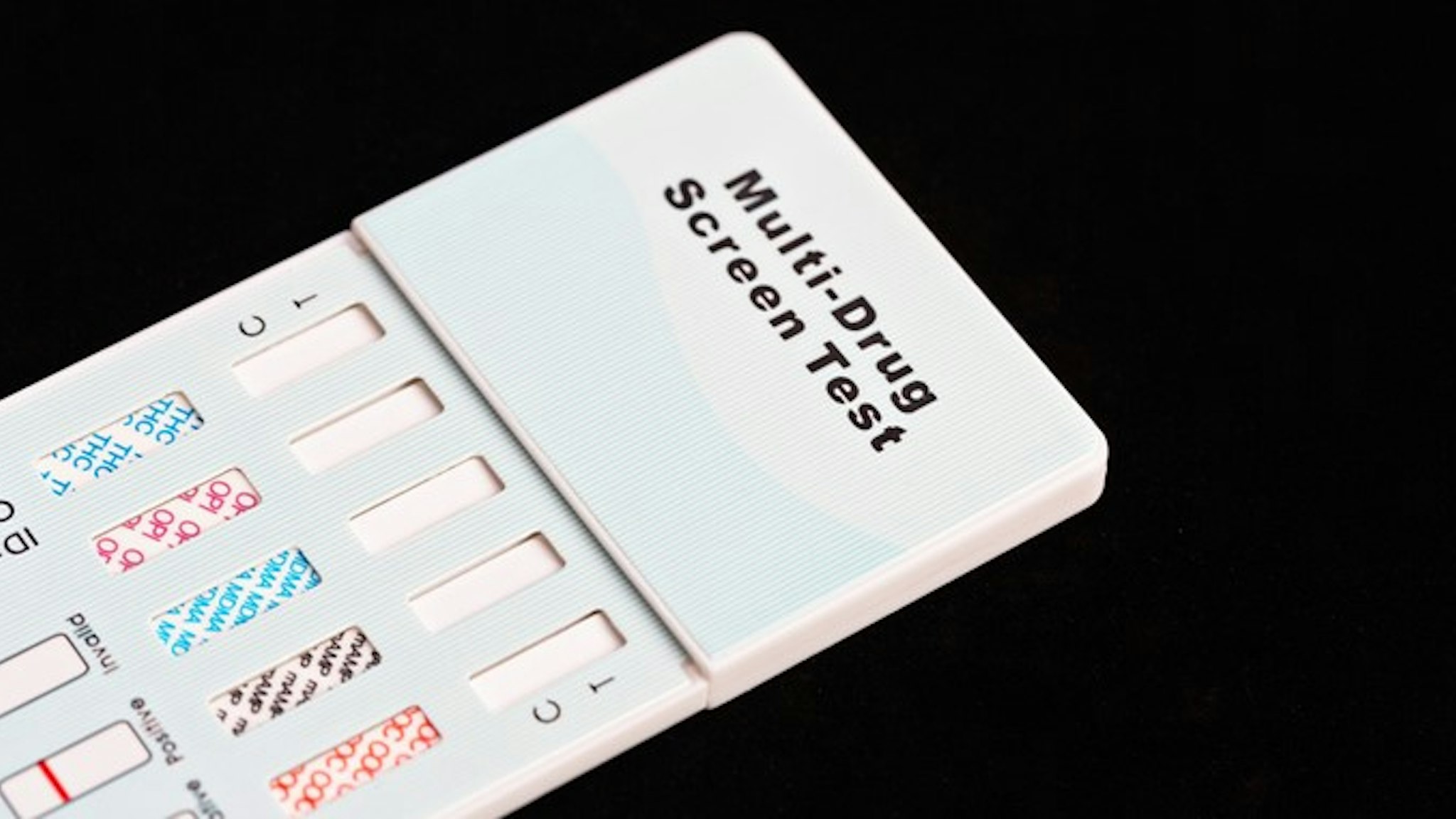 Cropped and angled view of a multi-drug urine testing kit, designed for use at home. This kit screens for cocaine, MDMA (E or Ecstasy), Methamphetamines (crystal meth or Tik), Opioids (including legal pharmaceuticals and heroin), and THC (cannabis, pot, grass, dagga) In today's world, many schools and responsible parents recommend using these kits routinely! Black background with copy space.