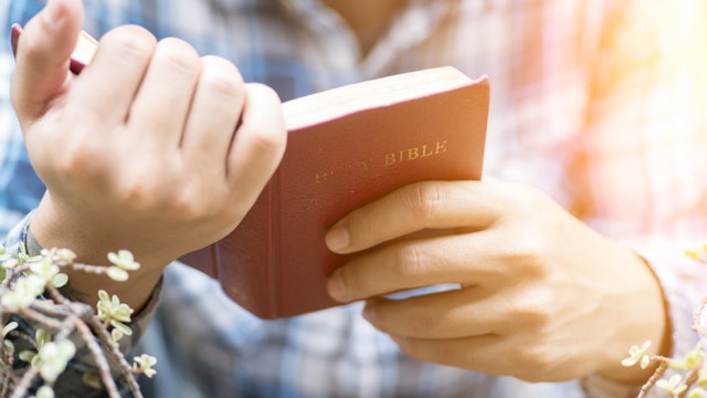 Human hand placed on the Bible, pray to God.