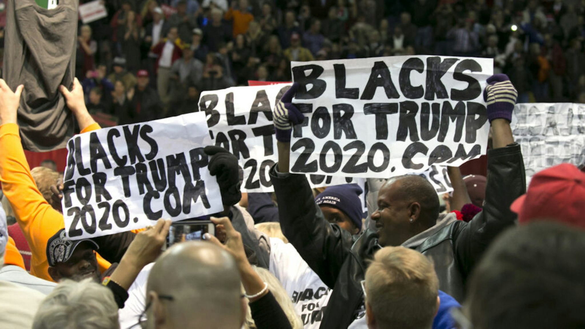Attendees hold "Blacks For Trump" during a campaign rally with U.S. President Donald Trump in Pensacola, Florida, U.S., on Friday, Dec. 8, 2017. Trump gave his most full-throated endorsement yet of Alabama Senate candidate Roy Moore, casting aside calls for to shun the former judge whos been accused of sexual misconduct while seizing on reports that questioned the credibility of his accuser.