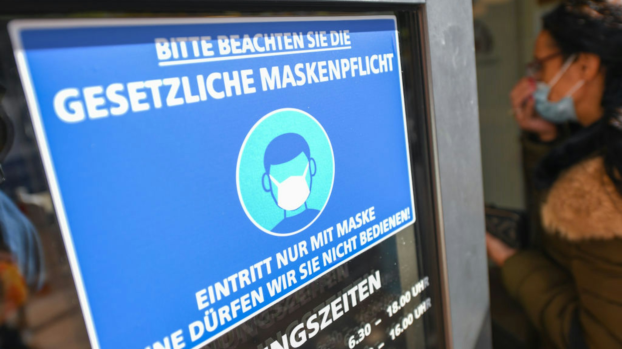 Rhineland-Palatinate, Mainz: A woman who wears a mouth and nose protector walks up to the entrance of a bakery at a sign saying "Please observe the legal obligation to wear a mask. Admission only with mask. Without it we are not allowed to serve you".