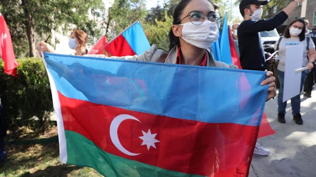 A member of Turkey and Azerbaijan Friendship Cooperation and Solidarity Foundation (TADIV) holds Azerbaijan's flag as she takes part in a protest outside the French Embassy in Ankara, Turkey on October 16, 2020. - Baku and Yerevan have for decades been locked in a simmering conflict over Nagorno-Karabakh, an ethnically Armenian region of Azerbaijan which broke away from Baku in a 1990s war that claimed the lives of some 30,000 people. The Caucasus neighbours have defied international calls to halt hostilities and accused the other of starting new clashes that began September 27 and have seen the heaviest fighting since a 1994 truce. (Photo by Adem ALTAN / AFP)