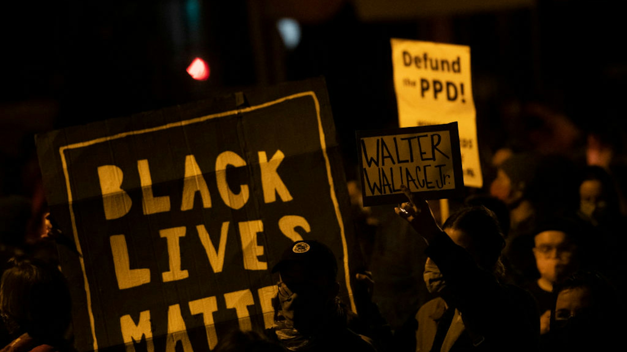 Demonstrators hold placards reading "BLACK LIVES MATTER," "Walter Wallace JR." and DEFUND PPD" as they gather in protest near the location where Walter Wallace, Jr. was killed by two police officers on October 27, 2020 in Philadelphia, Pennsylvania.