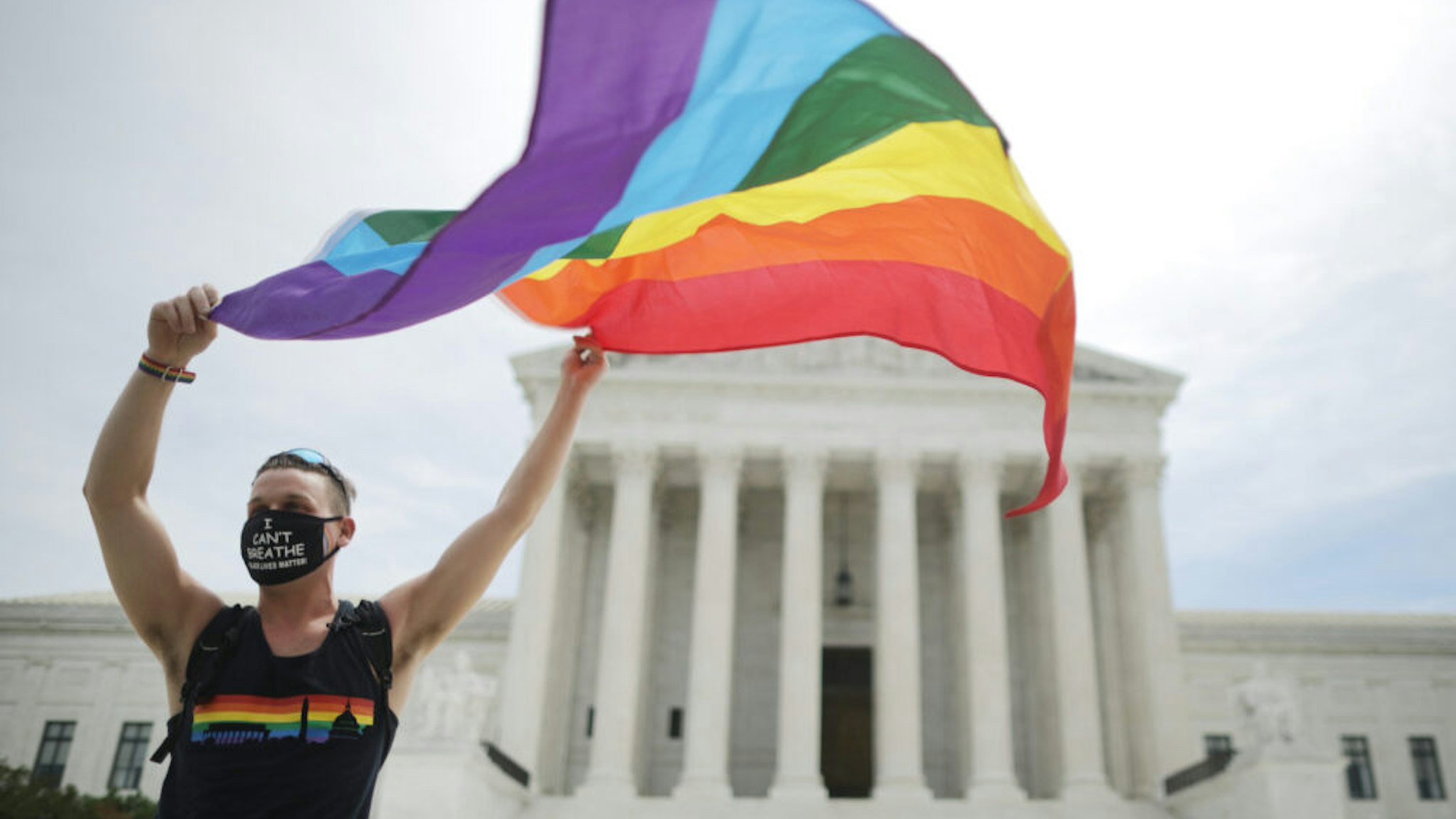 WASHINGTON, DC - JUNE 15: Joseph Fons holding a Pride Flag in front of the U.S. Supreme Court building after the court ruled that LGBTQ people can not be disciplined or fired based on their sexual orientation, Washington, DC, June 15, 2020. With Chief Justice John Roberts and Justice Neil Gorsuch joining the Democratic appointees, the court ruled 6-3 that the Civil Rights Act of 1964 bans bias based on sexual orientation or gender identity. Fons is wearing a Black Lives Matter mask with the words 'I Can't Breathe', as a precaution against Covid-19.