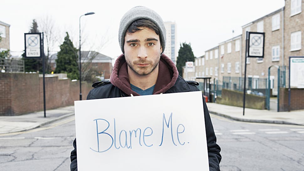 young man holding sign in urban street Blame Me
