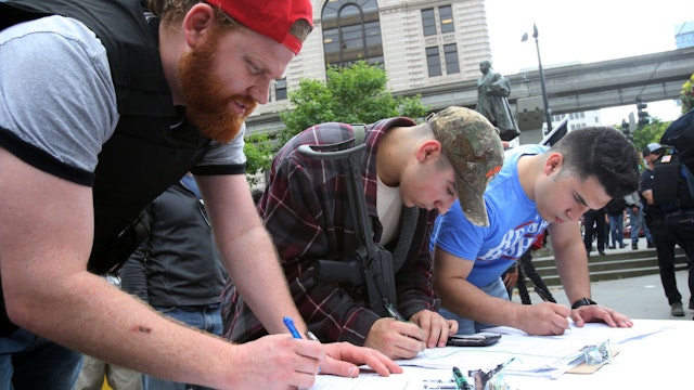 People participating in a guns rights rally sign a petition supporting Washington state Initiative 1621 that would allow people with a concealed pistol license to carry guns in schools during an open carry rally, on May 20, 2018 in Seattle, Washington.