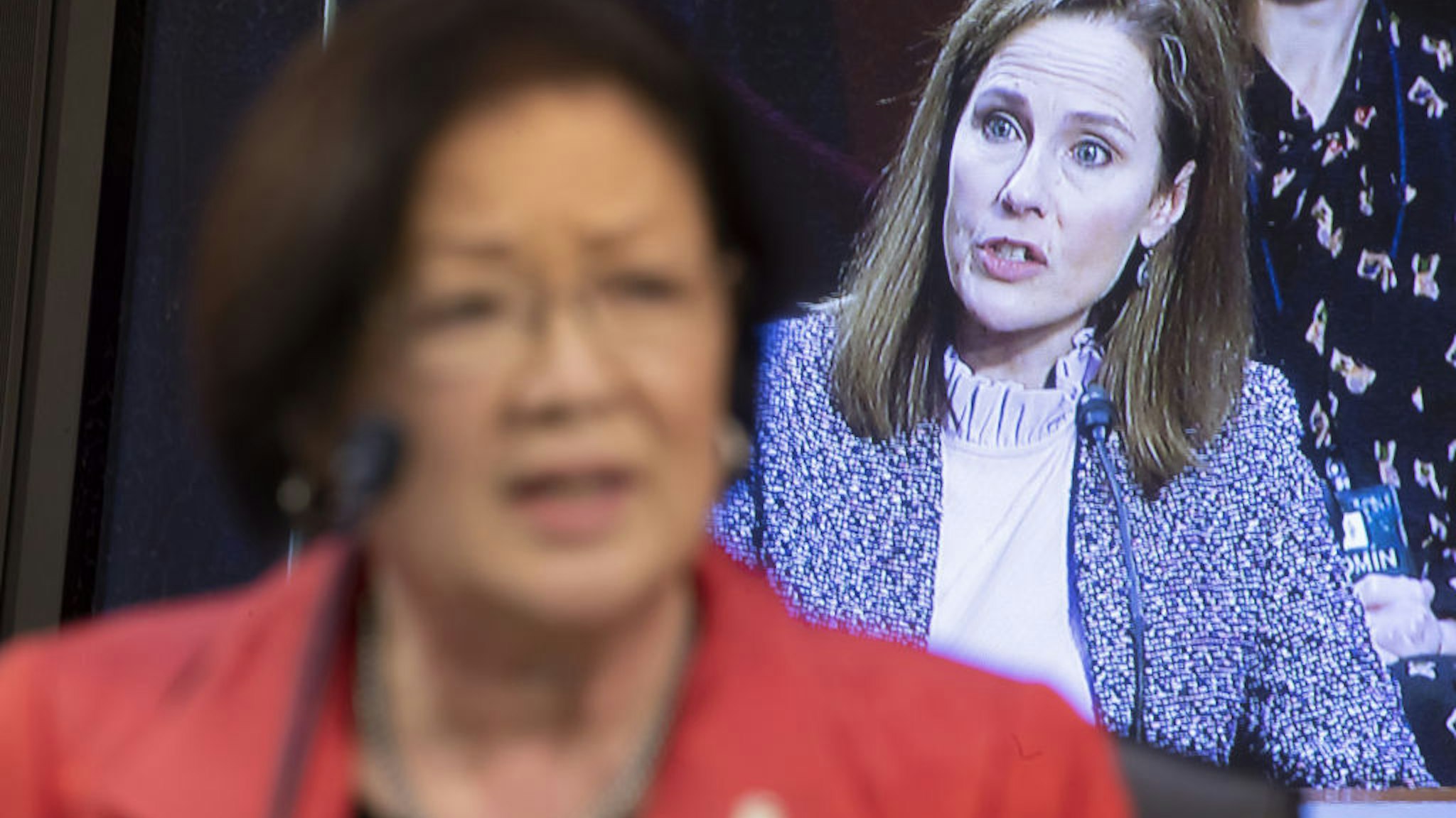 Amy Coney Barrett, U.S. President Donald Trump's nominee for associate justice of the U.S. Supreme Court, is displayed on a television monitor as Senator Mazie Hirono, a Democrat from Hawaii, left, speaks during a Senate Judiciary Committee confirmation hearing in Washington, D.C., U.S., on Wednesday, Oct. 14, 2020. Senate Democrats entered a second day of questioning Barrett having made few inroads in their fight to keep her off the Supreme Court and elicited few clues about how she would rule on key cases. Photographer: Michael Reynolds/EPA/Bloomberg