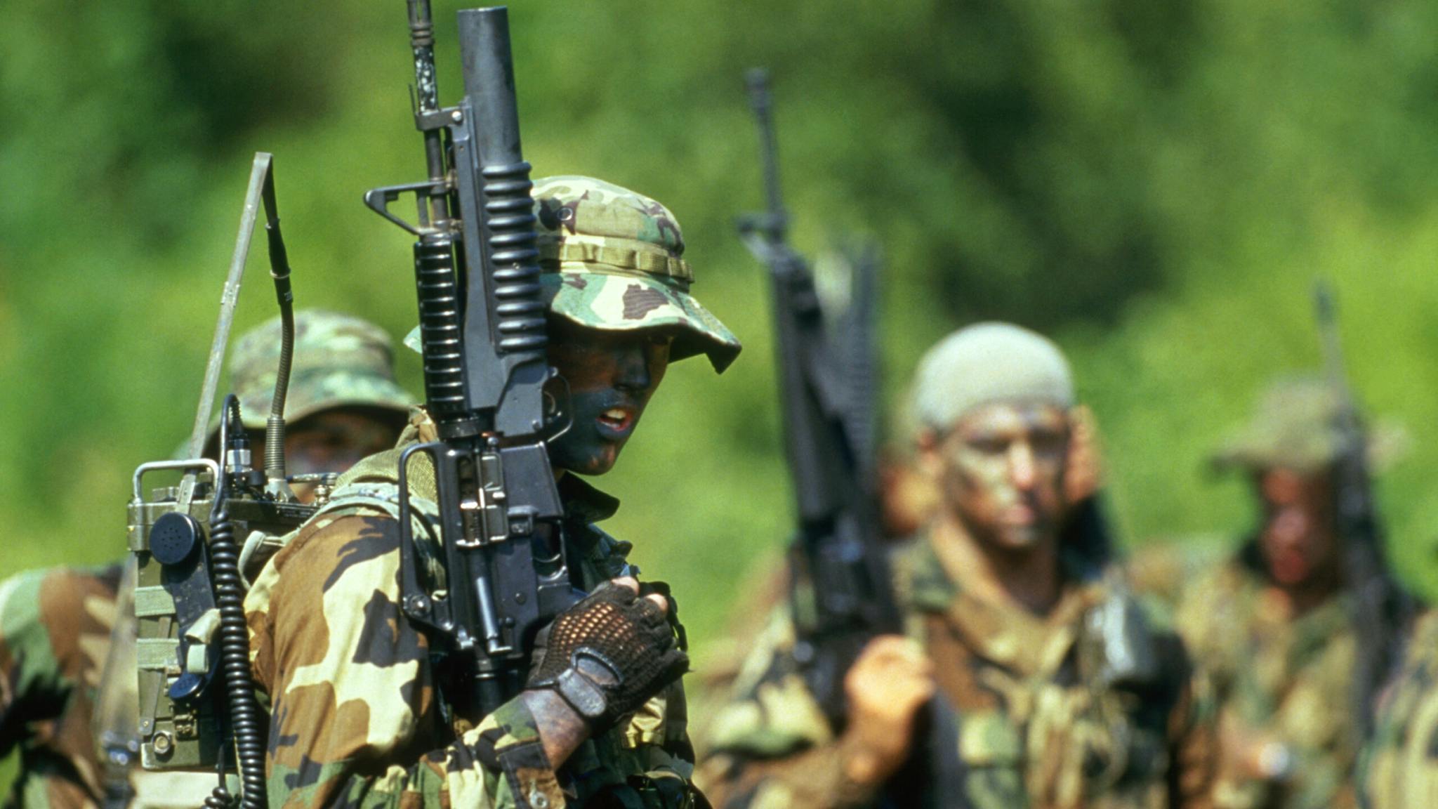 Navy SEALs U.S. Navy Sea-Air-Land (SEAL) team members participate in a tactical warfare training. The SEAL in the foreground is carrying a field radio and is armed with a Colt Commando assault rifle equipped with an M-203 grenade launcher.