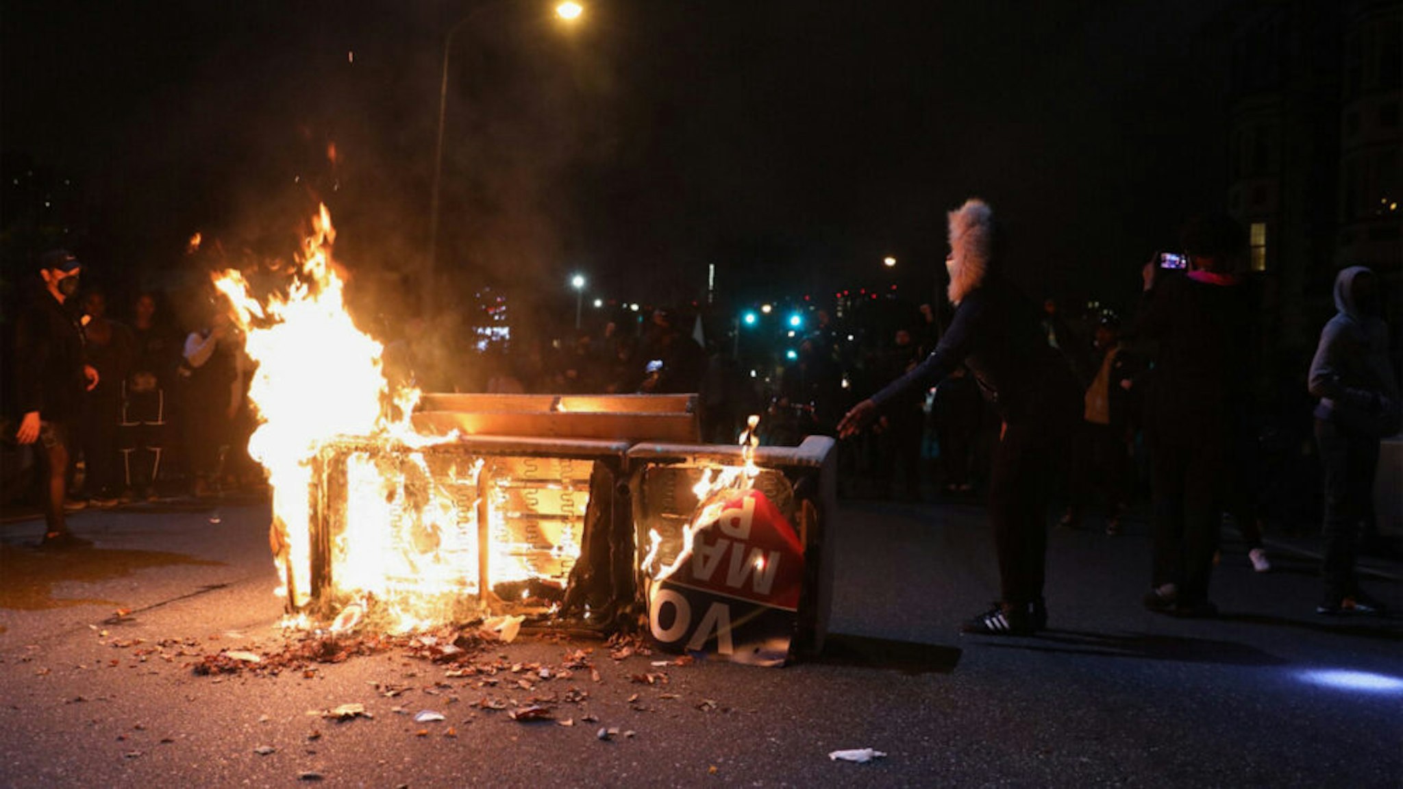 Demonstrators stand near a burning barricade in Philadelphia on October 27, 2020, during a protest over the police shooting of 27-year-old Black man Walter Wallace. - Hundreds of people demonstrated in Philadelphia late on October 27, with looting and violence breaking out in a second night of unrest after the latest police shooting of a Black man in the US. The fresh unrest came a day after the death of 27-year-old Walter Wallace, whose family said he suffered mental health issues. On Monday night hundreds of demonstrators took to the streets, with riot police pushing them back with shields and batons.