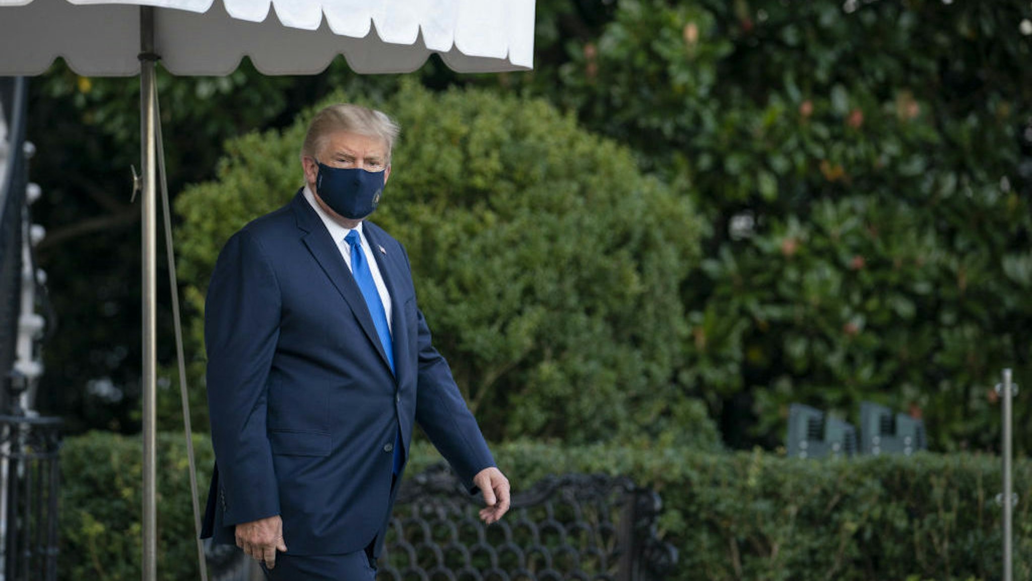 U.S. President Donald Trump wears a protective mask while walking to the South Lawn of the White House before boarding Marine One in Washington, D.C., U.S., on Friday, Oct. 2, 2020. Trump will be taken to Walter Reed National Military Medical Center to be treated for Covid-19, the White House said. Photographer: Sarah Silbiger/Bloomberg