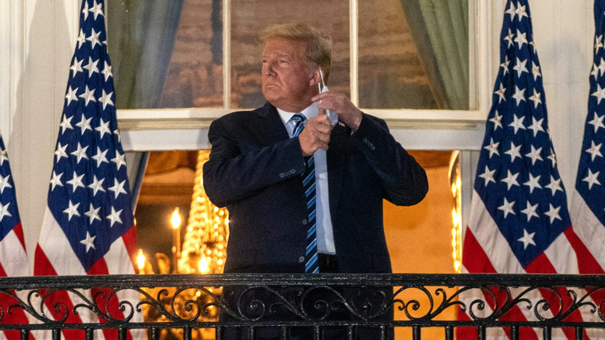 U.S. President Donald Trump removes his protective mask on the Truman Balcony of the White House in Washington, D.C., U.S., on Monday, Oct. 5, 2020. Trump's aides will try to keep him confined to the White House residence after being discharged from the hospital with Covid-19 but are unsure they can limit his movements.
