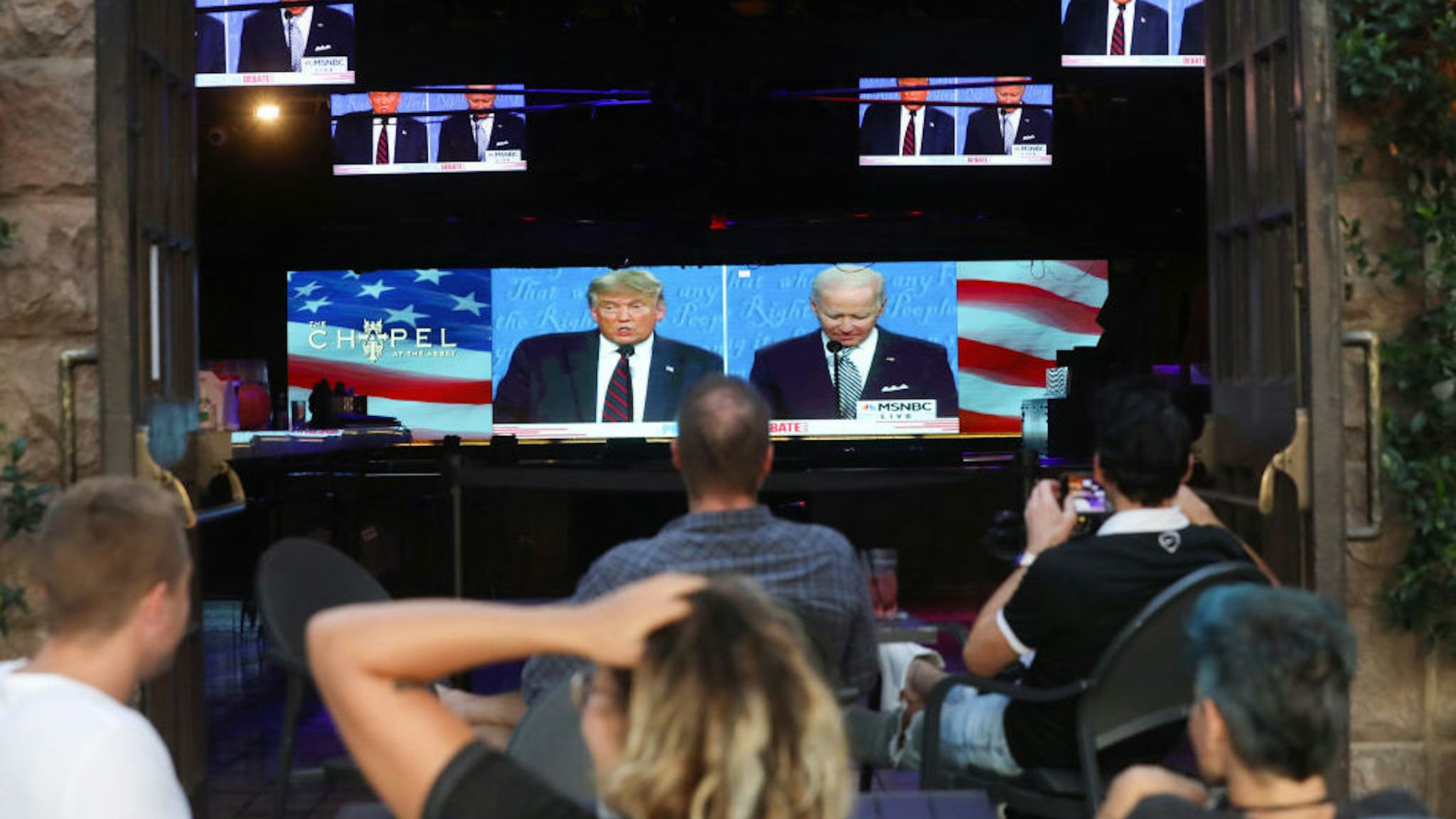 People sit and watch a broadcast of the first debate between President Donald Trump and Democratic presidential nominee Joe Biden at The Abbey, with socially distanced outdoor seating, on September 29, 2020 in West Hollywood, California. The debate being held in Cleveland, Ohio is the first of three scheduled debates between Trump and Biden. (Photo by Mario Tama/Getty Images)