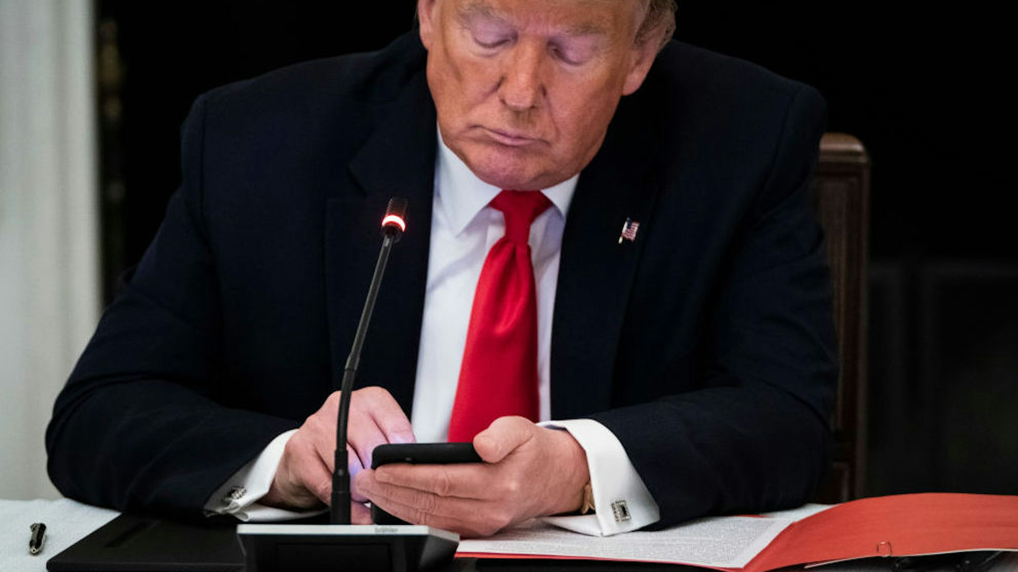 WASHINGTON, DC - JUNE 18: President Donald J. Trump uses his cellphone as he participates in a roundtable discussion with Governors and small business owners on the reopening of Americas small businesses in the State Dinning Room at the White House on Thursday, June 18, 2020 in Washington, DC.