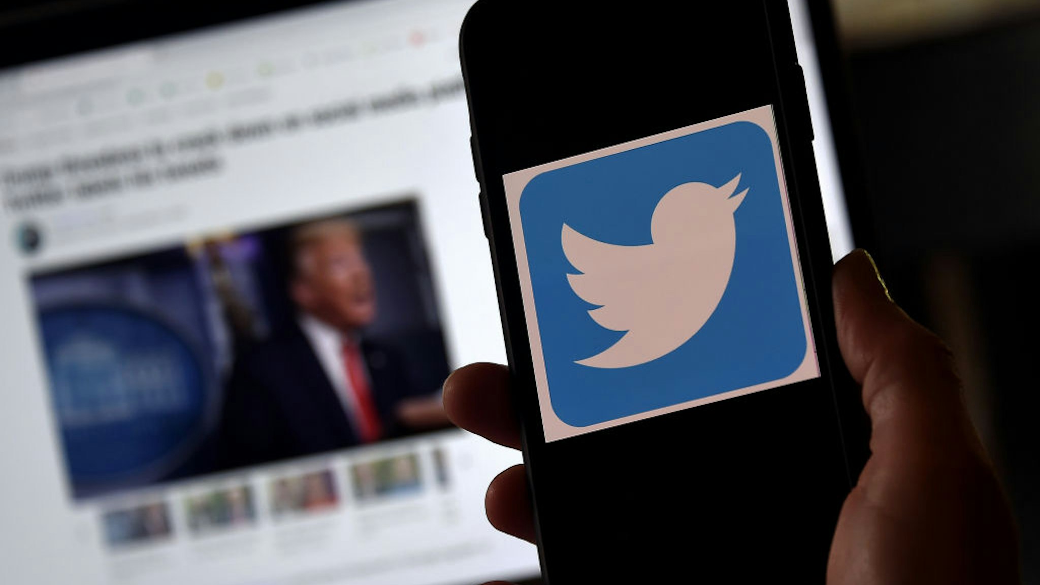 In this photo illustration, a Twitter logo is displayed on a mobile phone with President Trump's Twitter page shown in the background on May 27, 2020, in Arlington, Virginia. - US President Donald Trump threatened Wednesday to shutter social media platforms after Twitter for the first time acted against his false tweets, prompting the enraged Republican to double down on unsubstantiated claims and conspiracy theories. Twitter tagged two of Trump's tweets in which he claimed that more mail-in voting would lead to what he called a "Rigged Election" this November. (Photo by Olivier DOULIERY / AFP) (Photo by OLIVIER DOULIERY/AFP via Getty Images)