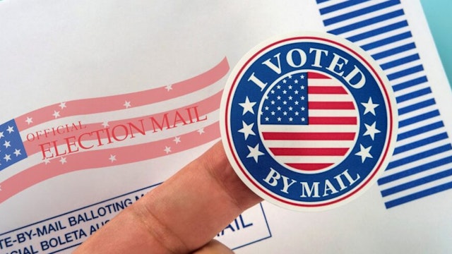 Human finger holding sticker above voting mail