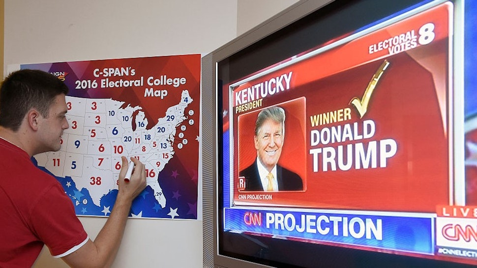 TOPSHOT - Jake Krupa colors in an electoral map as states are projected for Republican presidential candidate Donald Trump or Democratic Presidential candidate Hillary Clinton at an election watching party in Coconut Grove, Florida, on November 8, 2016. / AFP / RHONA WISE (Photo credit should read