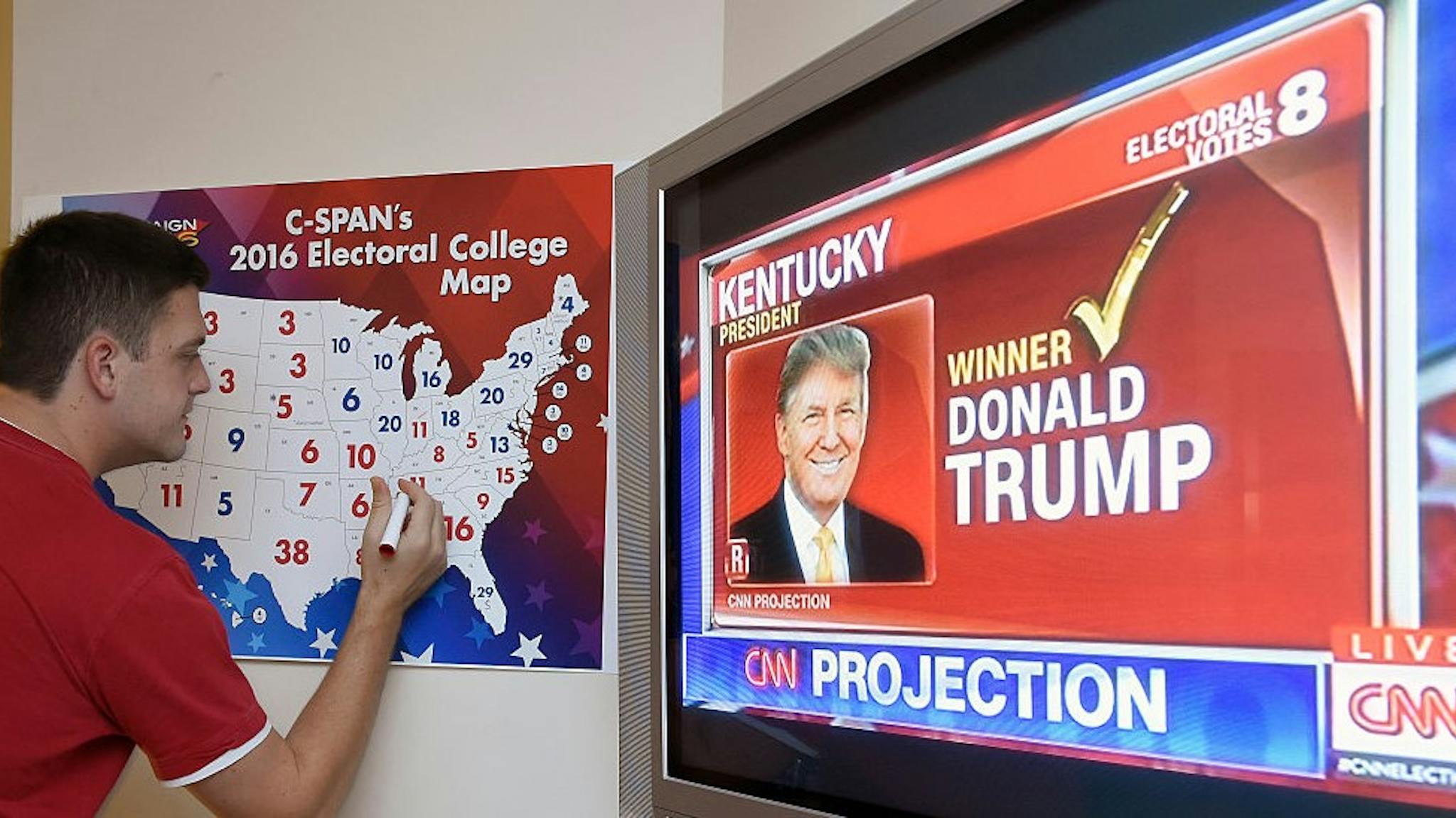 TOPSHOT-US-VOTE-ELECTION TOPSHOT - Jake Krupa colors in an electoral map as states are projected for Republican presidential candidate Donald Trump or Democratic Presidential candidate Hillary Clinton at an election watching party in Coconut Grove, Florida, on November 8, 2016. / AFP / RHONA WISE (Photo credit should read